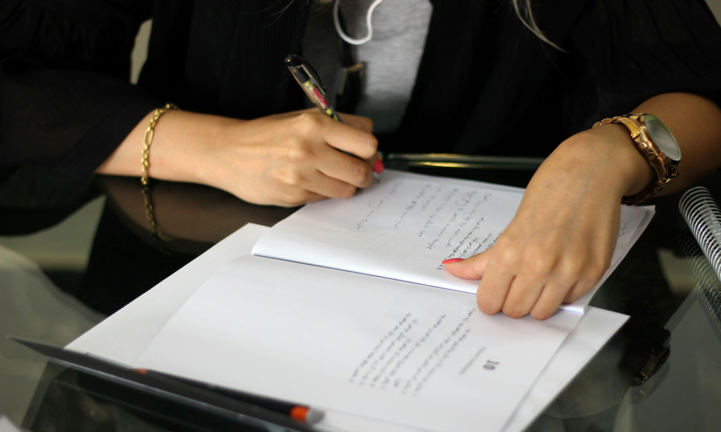 Close-up of a person's hand turning pages in a Bible, with a smartphone visible on a table nearby.
