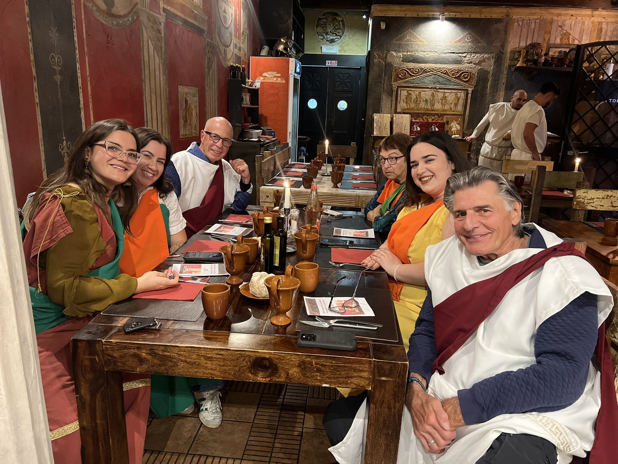 Two women sitting at a restaurant table with food and drinks, smiling at the camera.