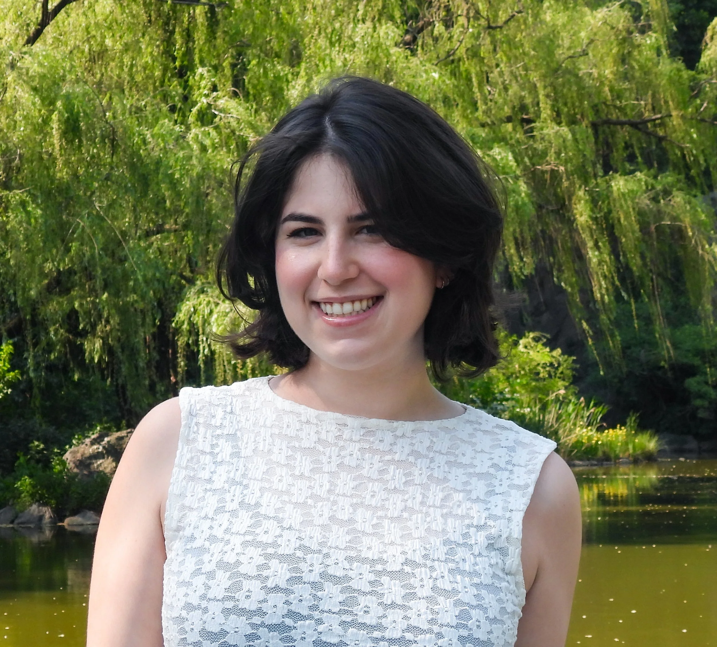Jenna Kupferschmid, a young woman with long dark hair smiling, wearing a dress standing in a park.