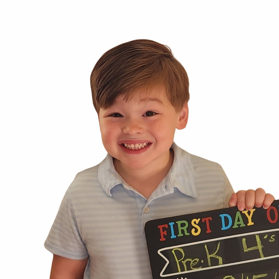 Smiling child holding a "First Day of Pre-K" sign.