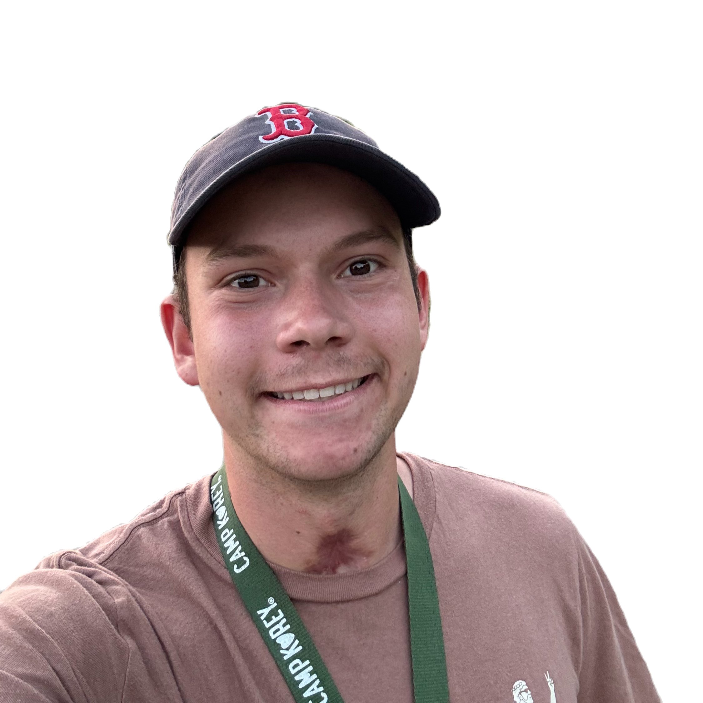 Young person wearing a Boston Red Sox cap and a brown shirt, smiling with a lanyard around their neck. White background.