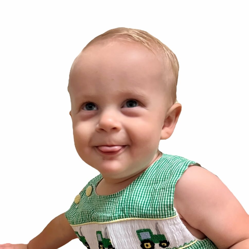 Baby with blond hair wearing a green and white gingham outfit on a white background.
