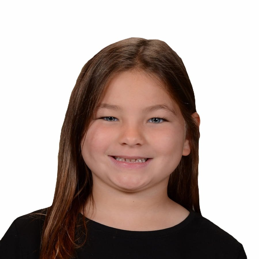 Smiling child with long hair, wearing a black shirt, on a white background.
