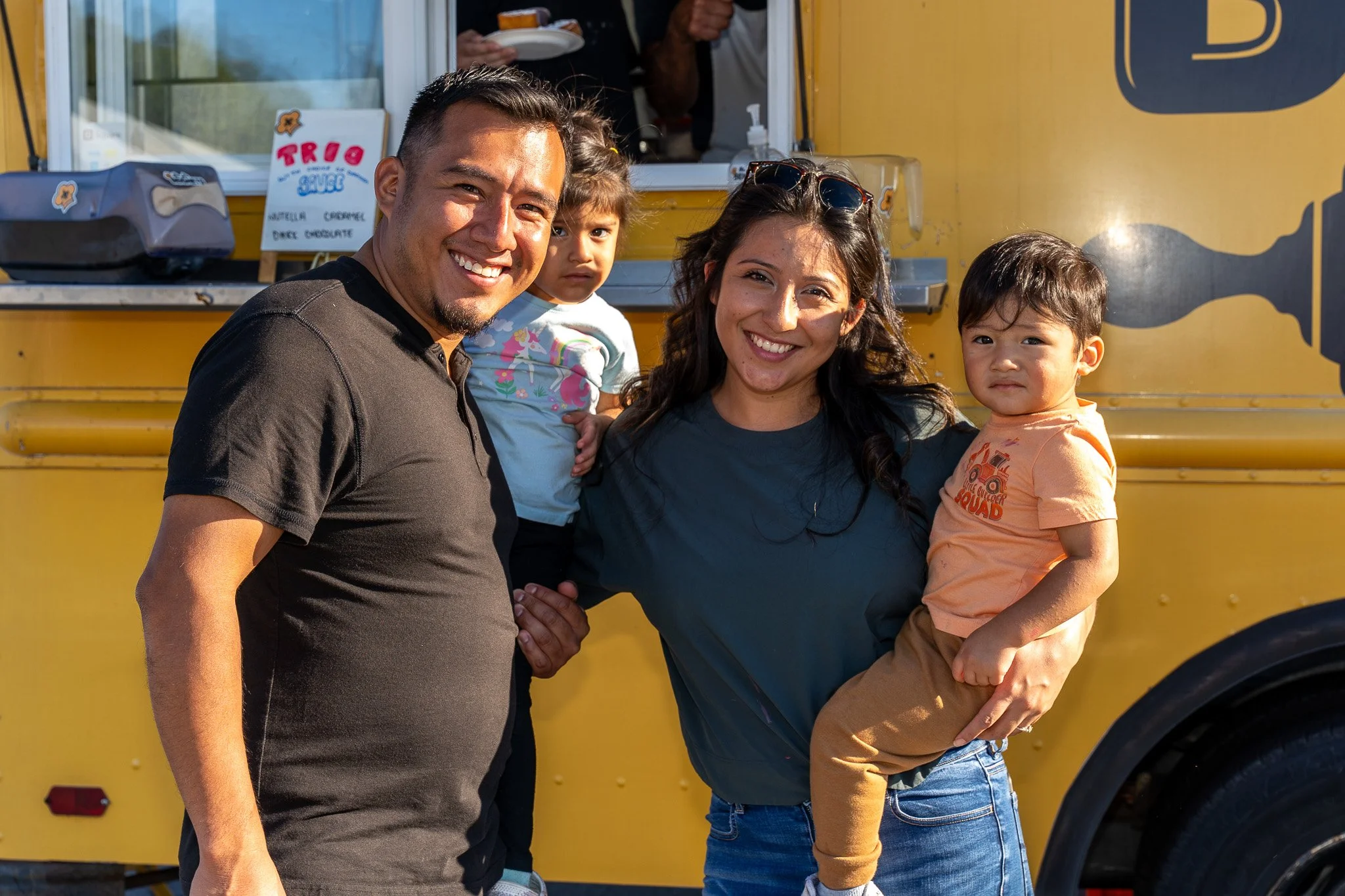 Family posing in front of a yellow food truck