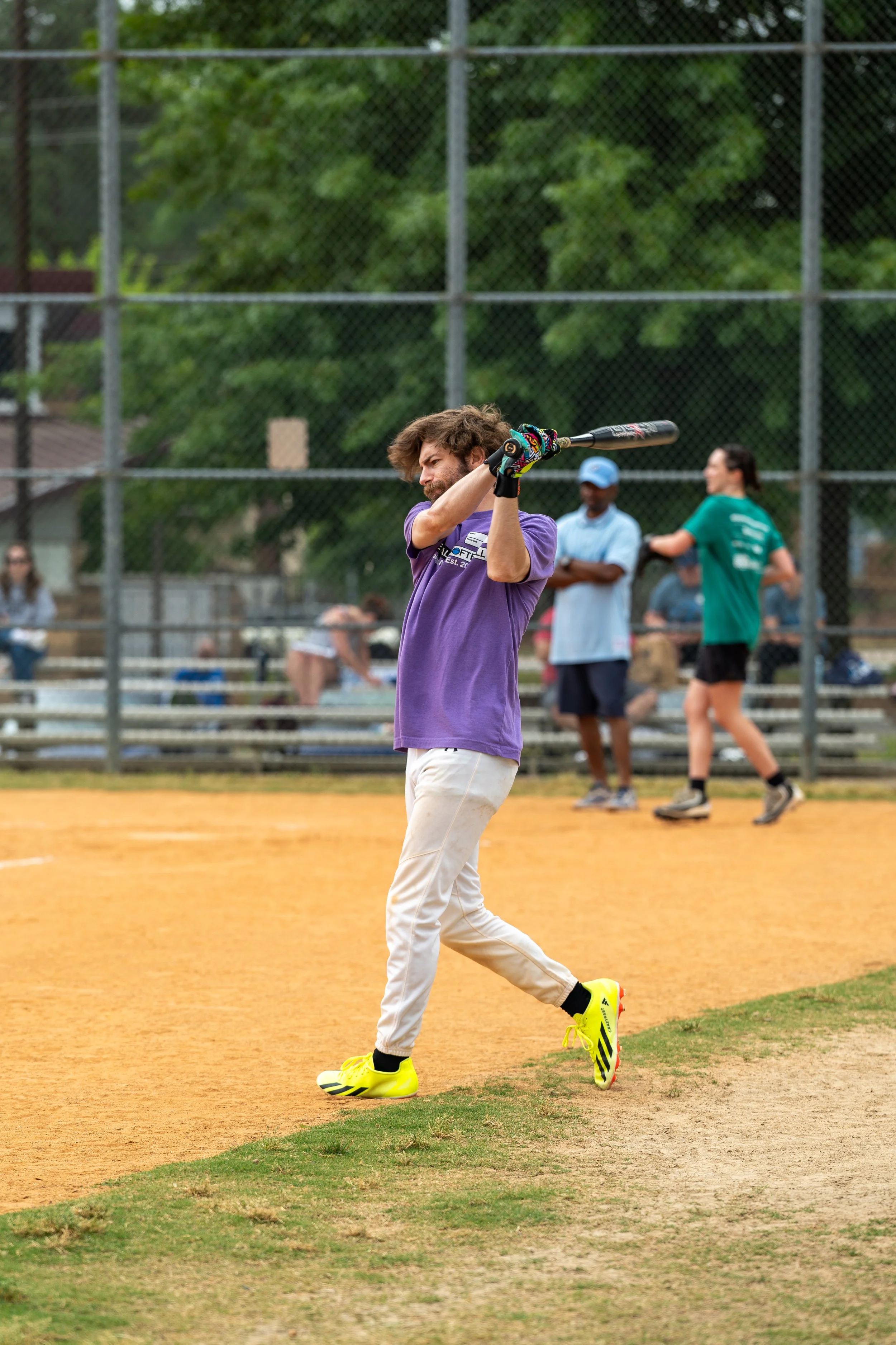A person swinging a bat on a baseball field with others in the background.