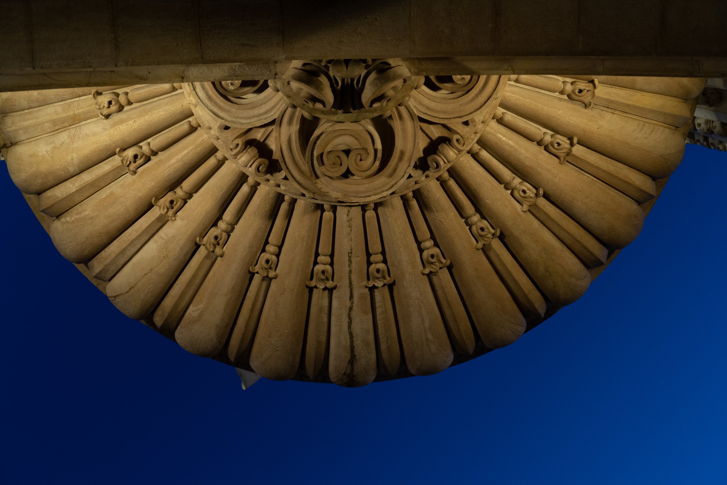 Decorative stone ceiling detail with circular pattern against night sky.
