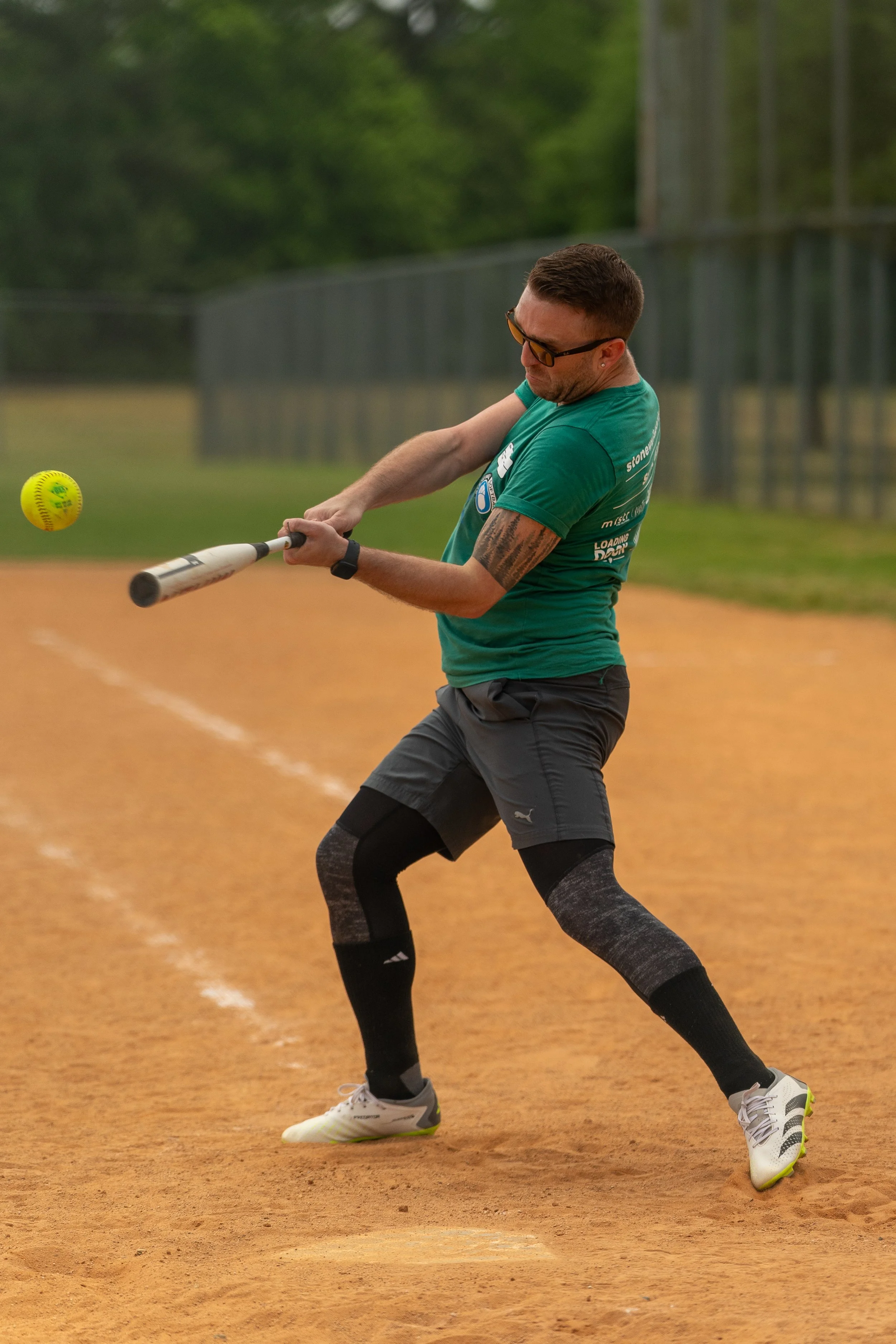 Person playing softball swinging bat on field