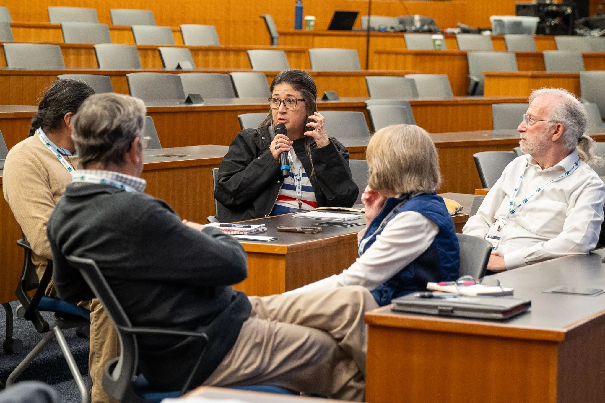Group of people in conference room discussing, one holding a microphone
