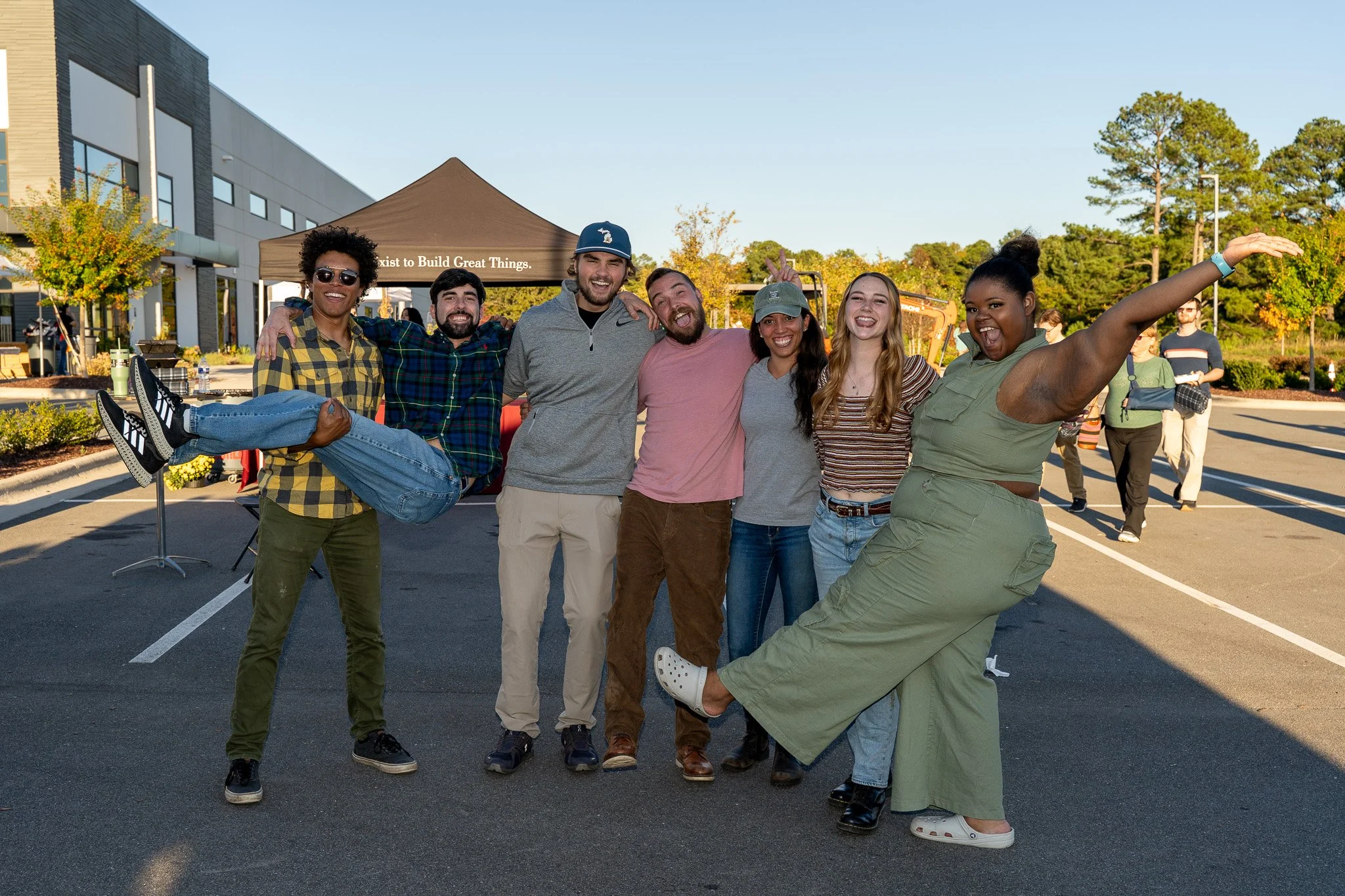 Group of friends posing playfully outdoors in a parking lot at a community event
