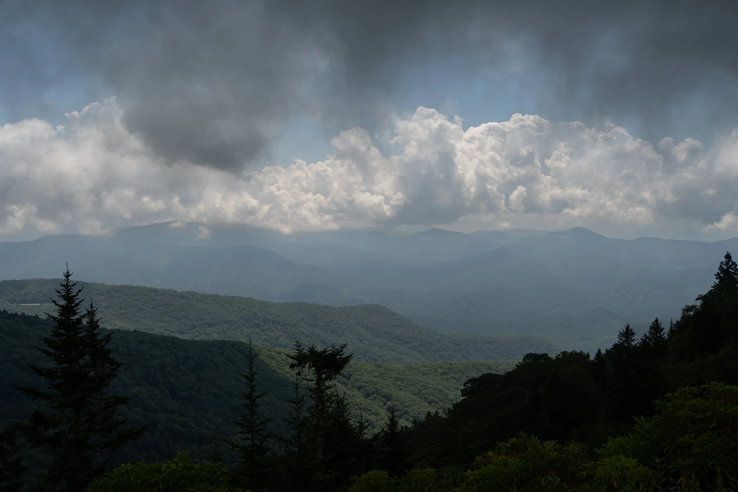 Dense forested mountains under cloudy sky
