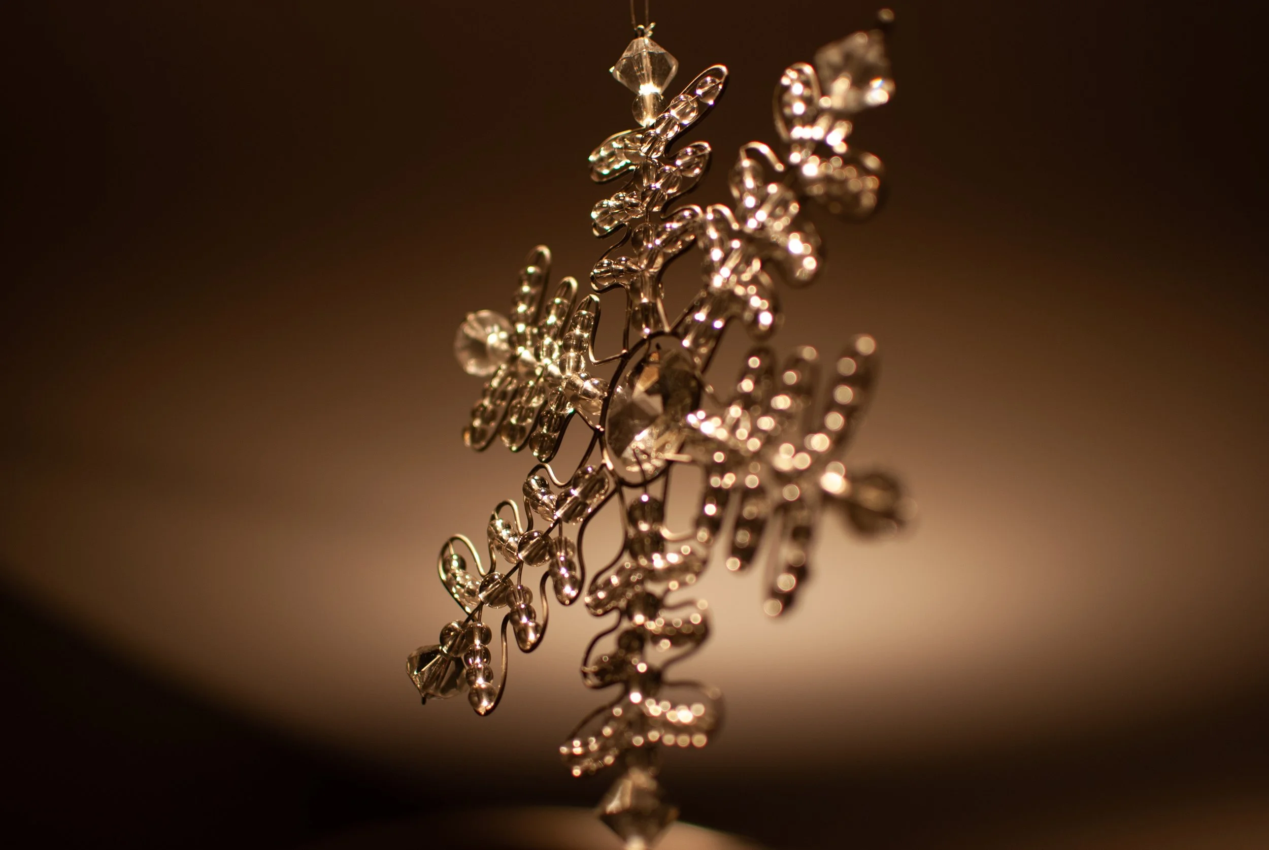 Close-up of a decorative glass snowflake ornament with a blurred background.