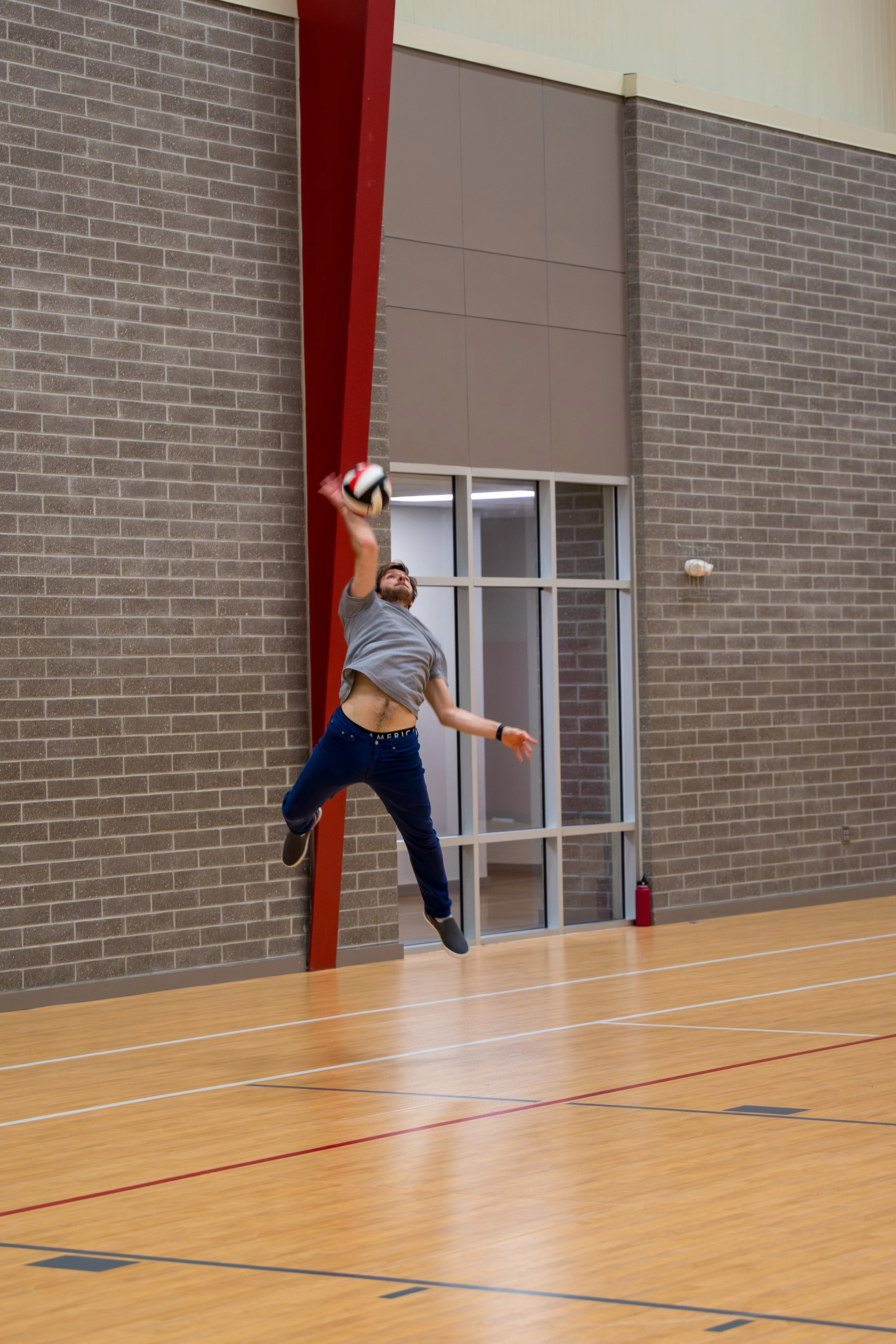 Person jumping to spike a volleyball indoors on a court.