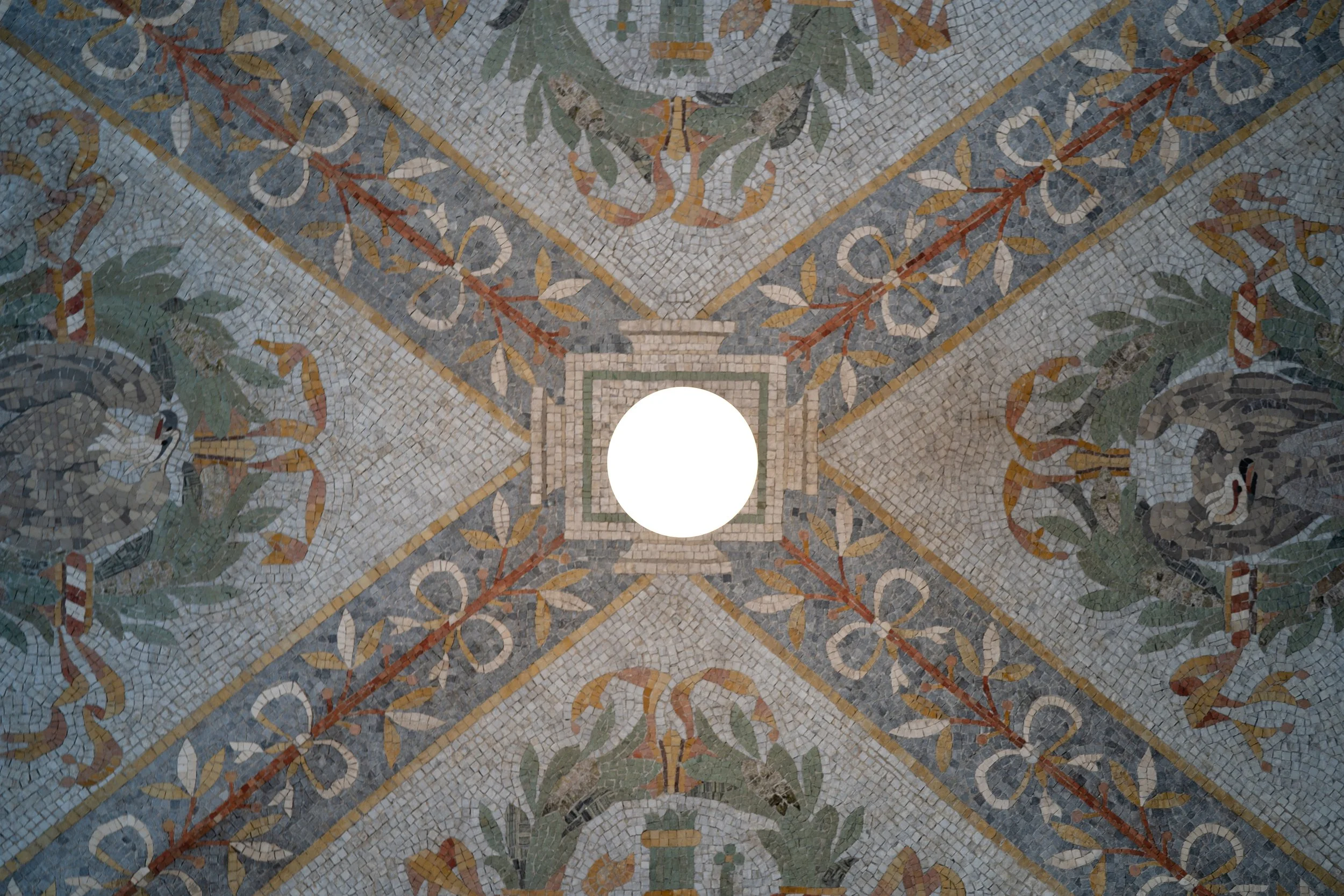 Ornate mosaic ceiling with floral and geometric patterns, centered circle opening