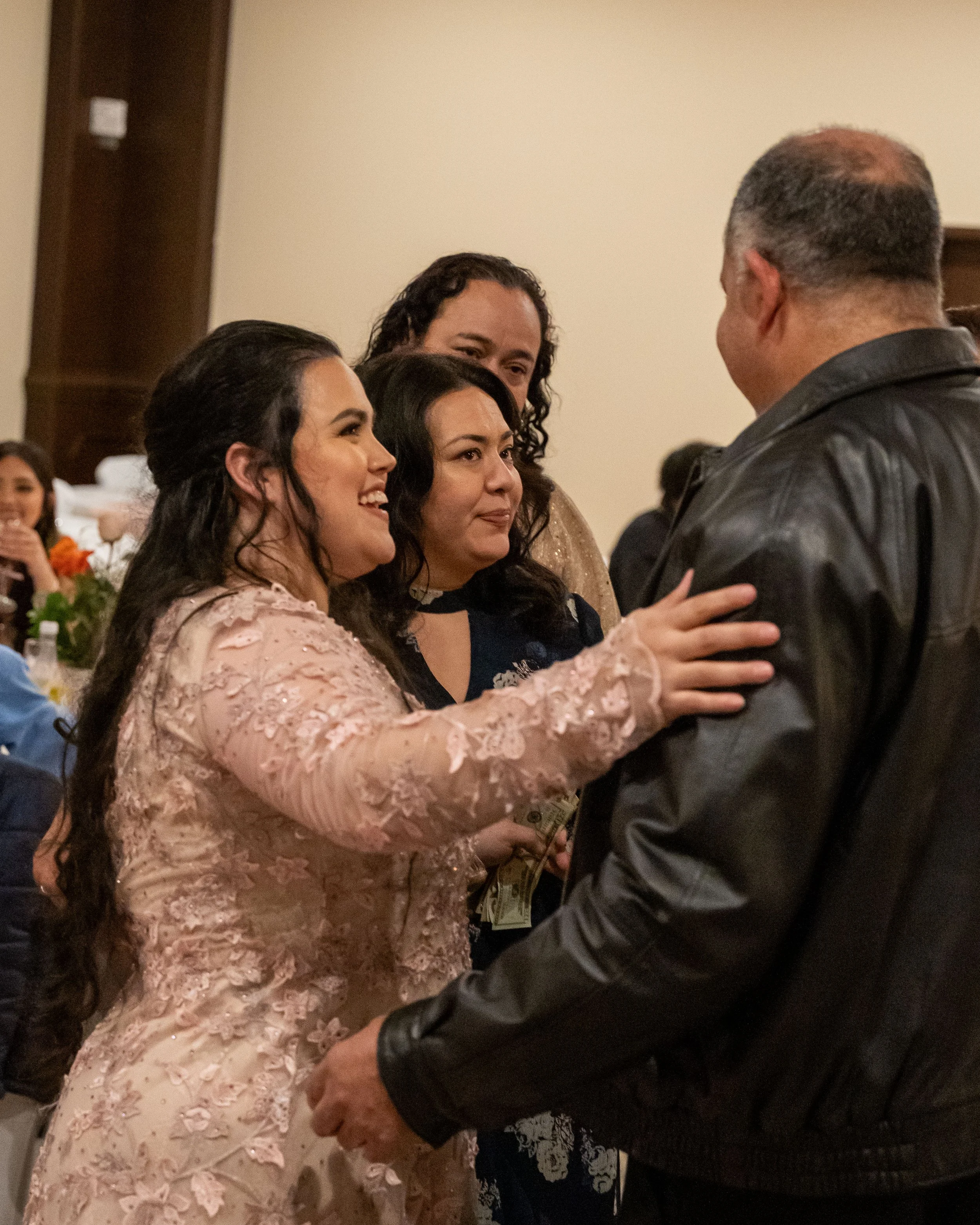 Group of people embracing and celebrating at an indoor wedding reception