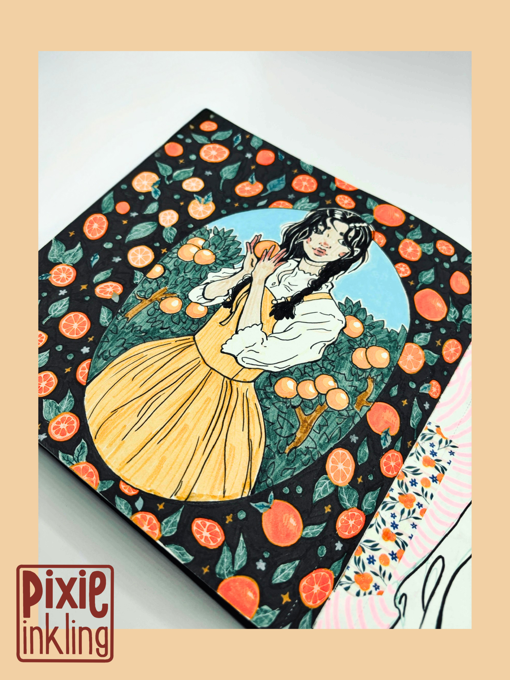 An illustration in a sketchbook featuring a woman with black hair in a braid, wearing a yellow dress, holding an orange, surrounded by oranges and orange leaves, with a light blue circle background and a dark border with orange slices and leaves.
