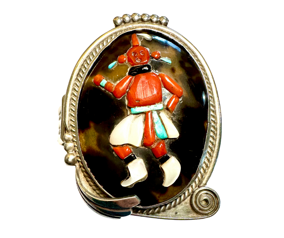 A vintage brooch featuring a colorful, stylized dancing figure in traditional clothing with a silver decorative border.