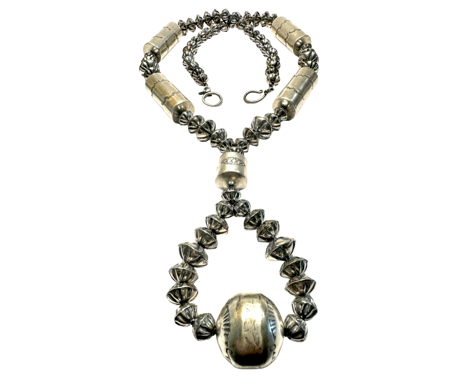 A metallic beaded necklace with a large clasp at the bottom, arranged in a heart shape with a cross loop at the top, on a black background.