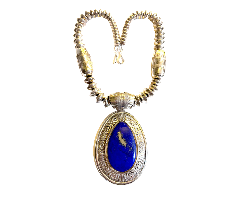 A silver necklace with a heart-shaped design made of rounded beads and a pendant featuring a large oval blue stone with gold accents.