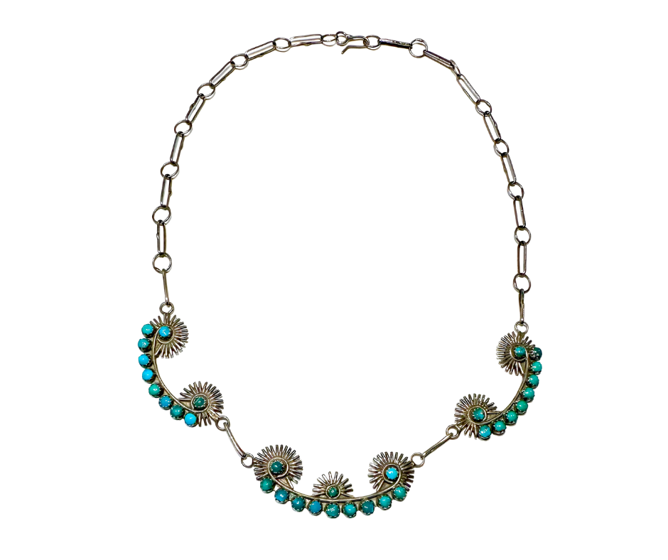 A silver necklace with a floral design, featuring turquoise and dark green beads.