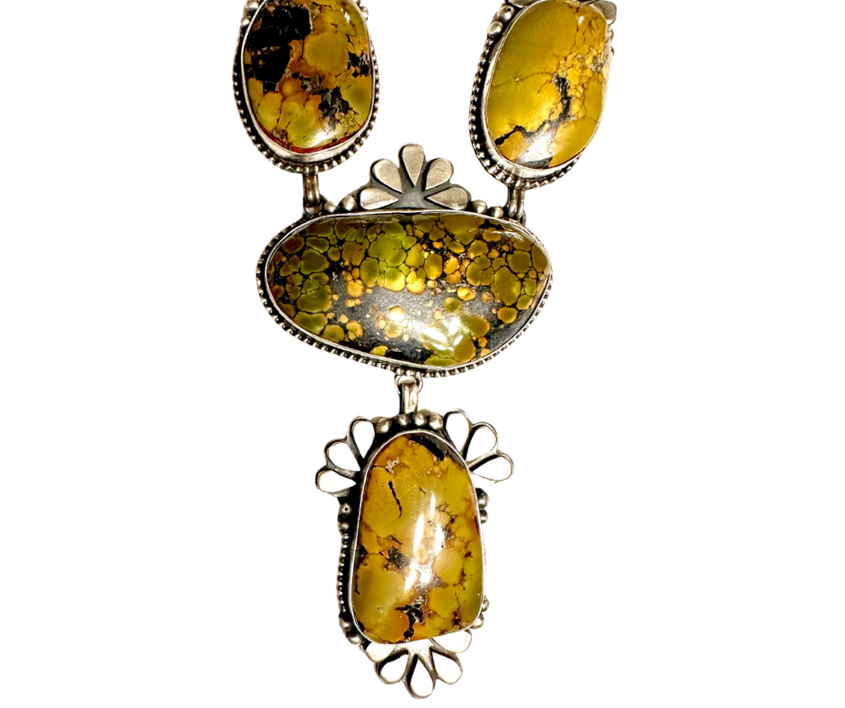 A silver jewelry piece with five turquoise stones, set in a decorative design.