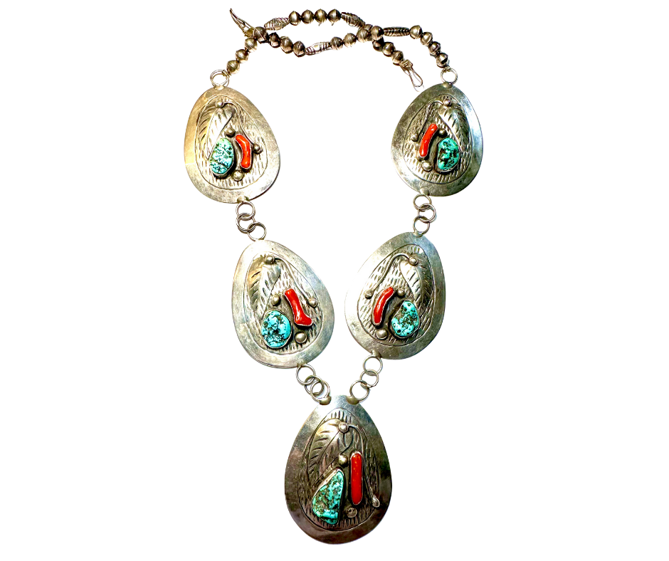 A vintage-style necklace with oval silver pendants. Each pendant features a turquoise stone and a red coral accent, connected by small metal links.