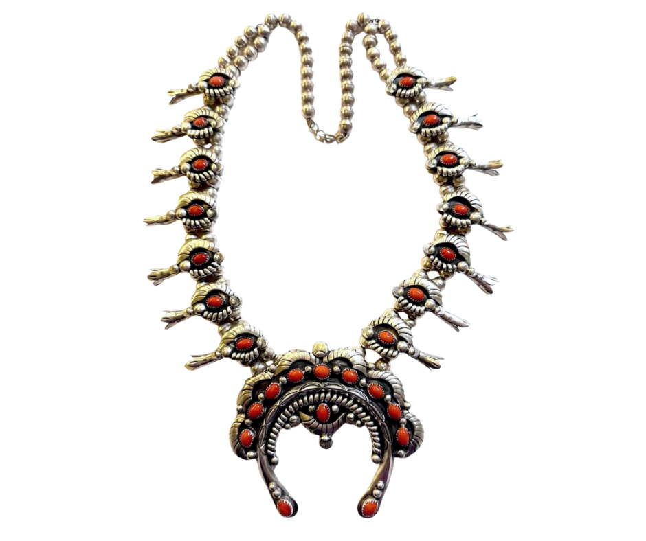 A silver necklace with red gemstones, featuring a large circular pendant. The necklace is designed with skull motifs around the chain.