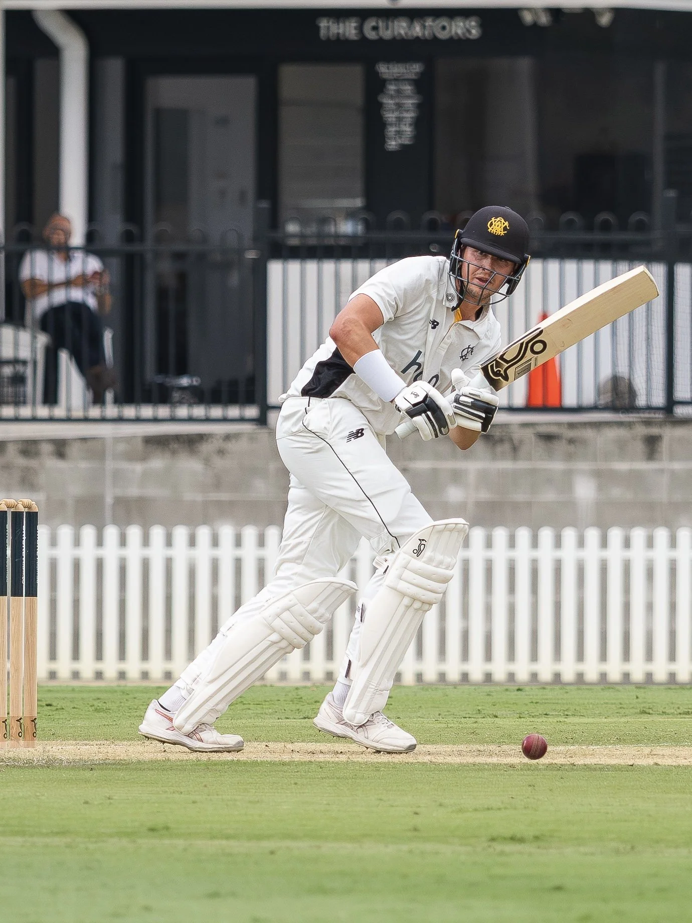 A cricket player in white uniform and helmet runs after hitting the ball on the pitch.