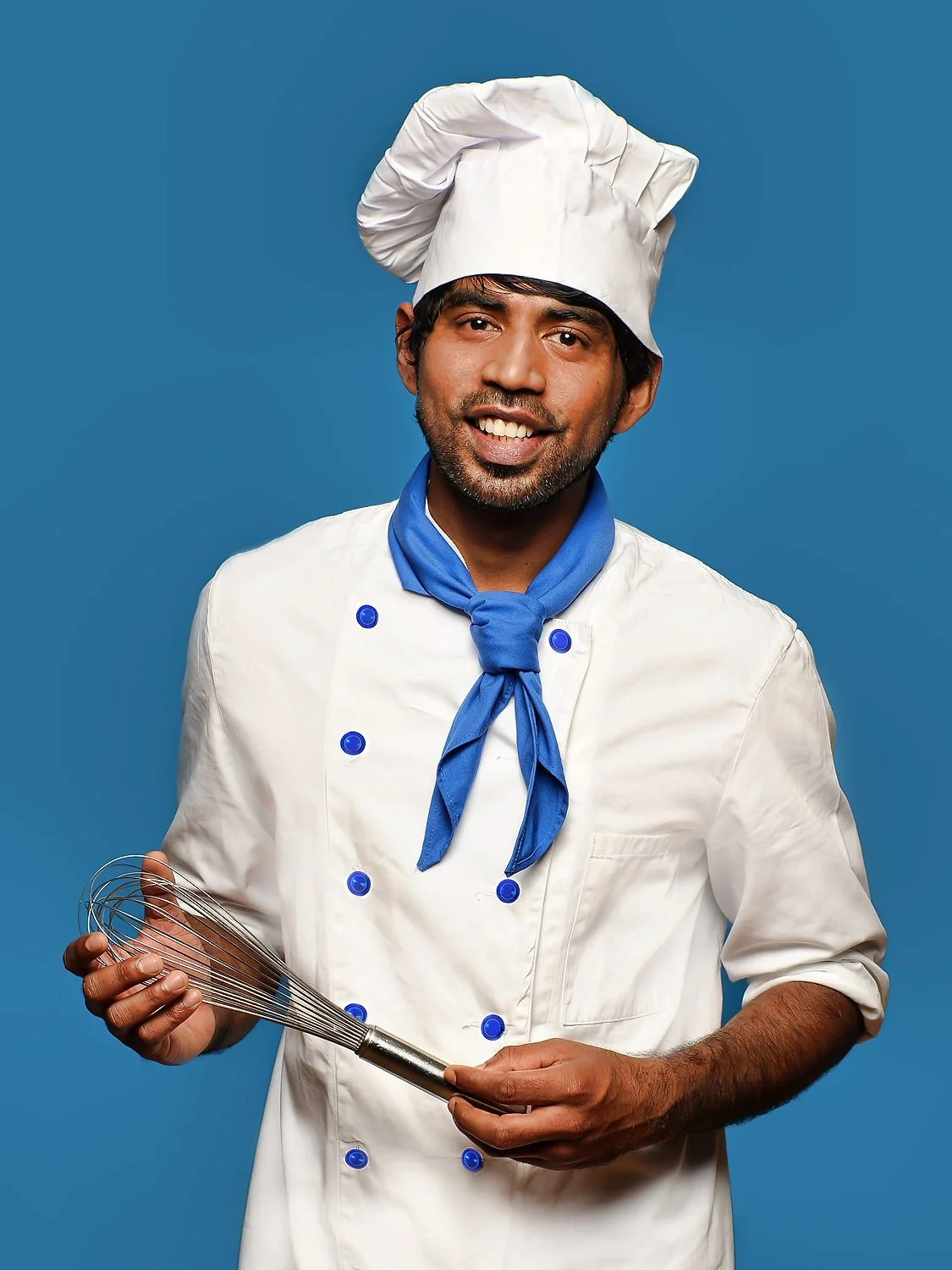 Fot eines Kochs Mit blauem Halstuch blauen Knöpfen an der Jacke vor blauem Hintergrund