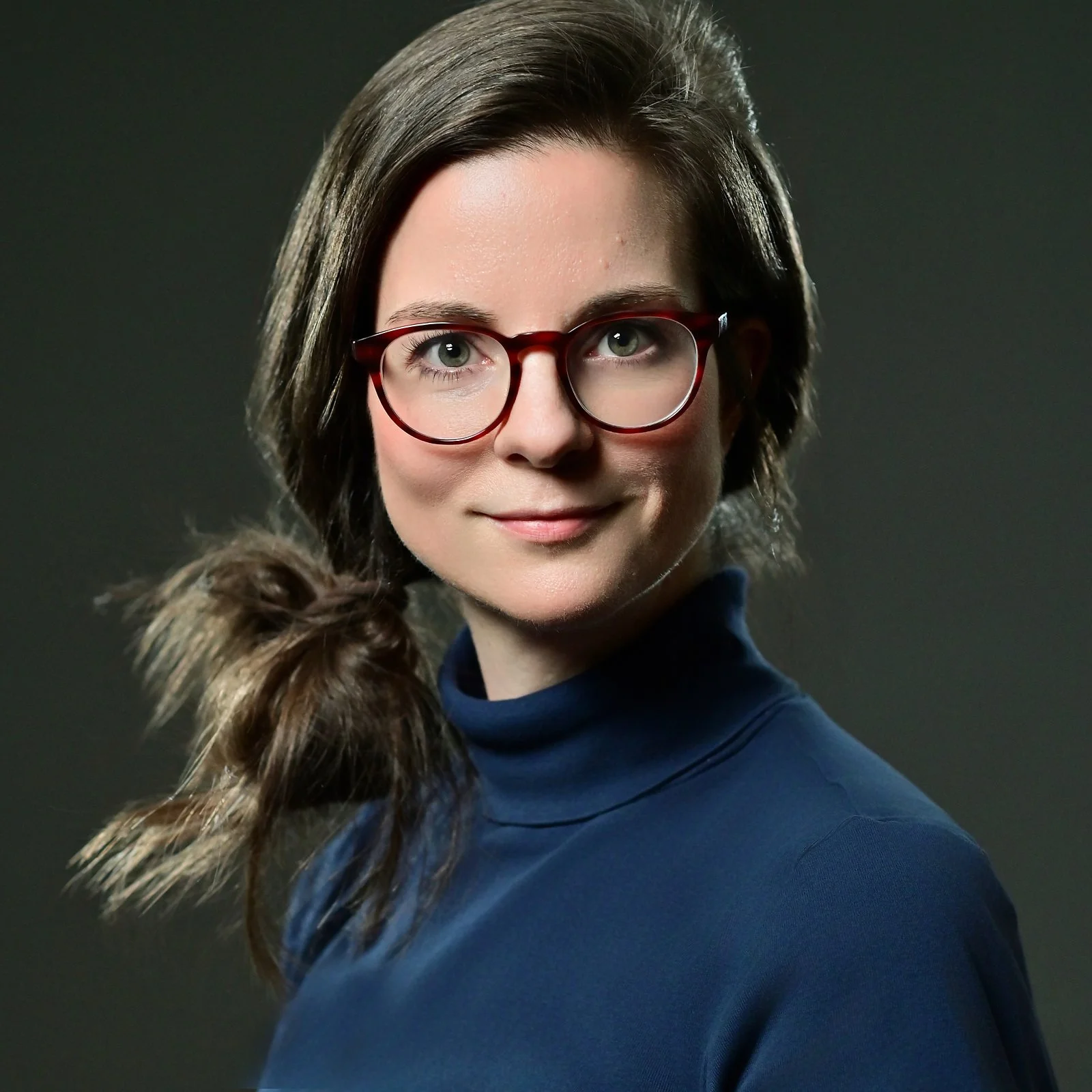 Portrait einer Dame mit Brille vor dunklem Hintergrund