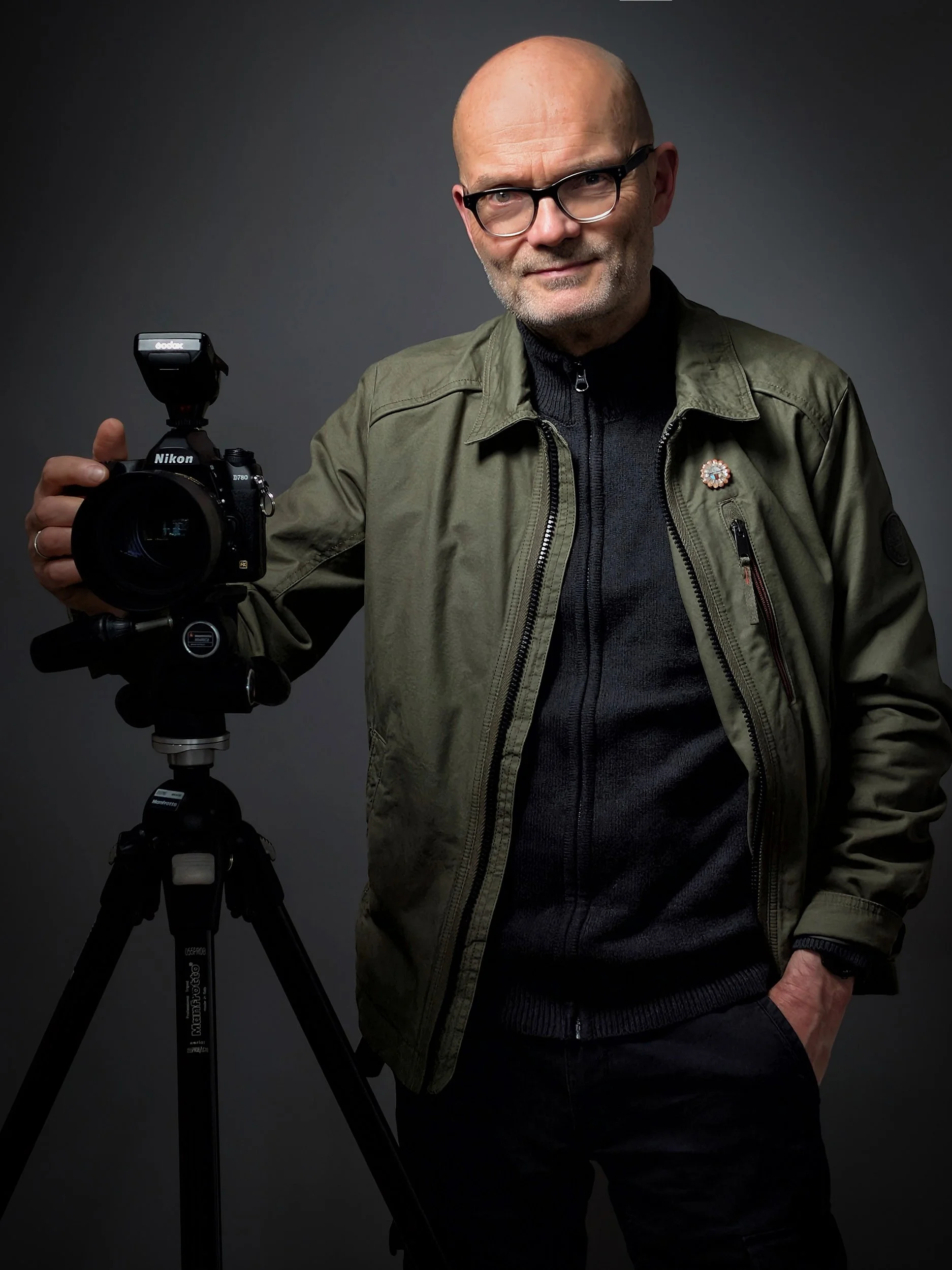Foto des Fotografen Michael Kleinespel. Seine Hand liegt auf einer Kamera, die sich auf einem Stativ befindet.