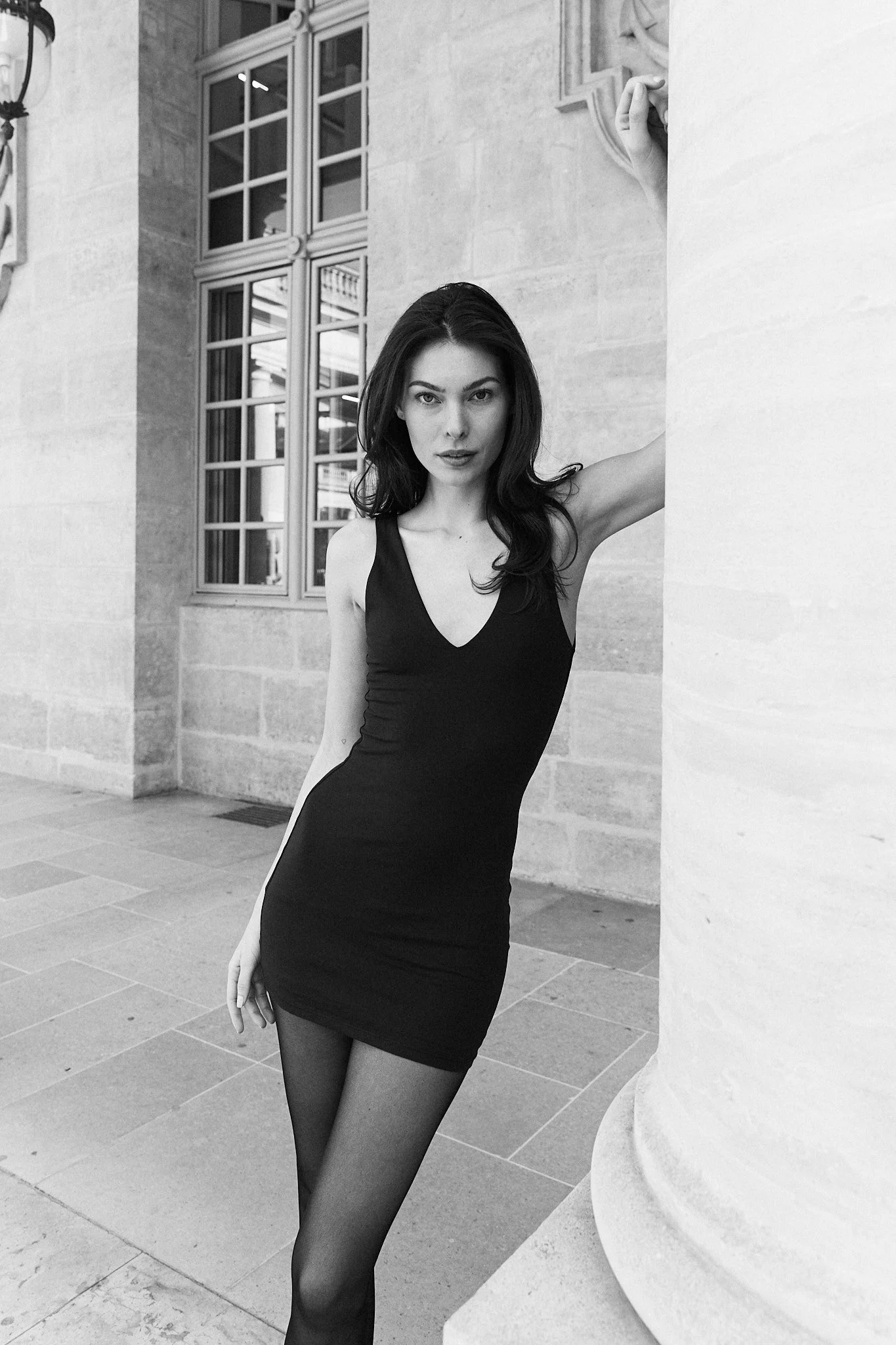 medium shot in black and white of model in black dress in Paris posing near the Louvre