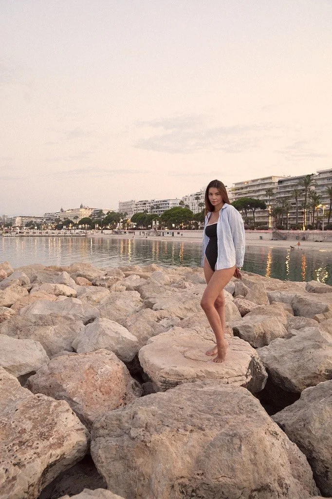 Portrait large de modèle photo sur les rochers avec une vue sur les plages de Cannes