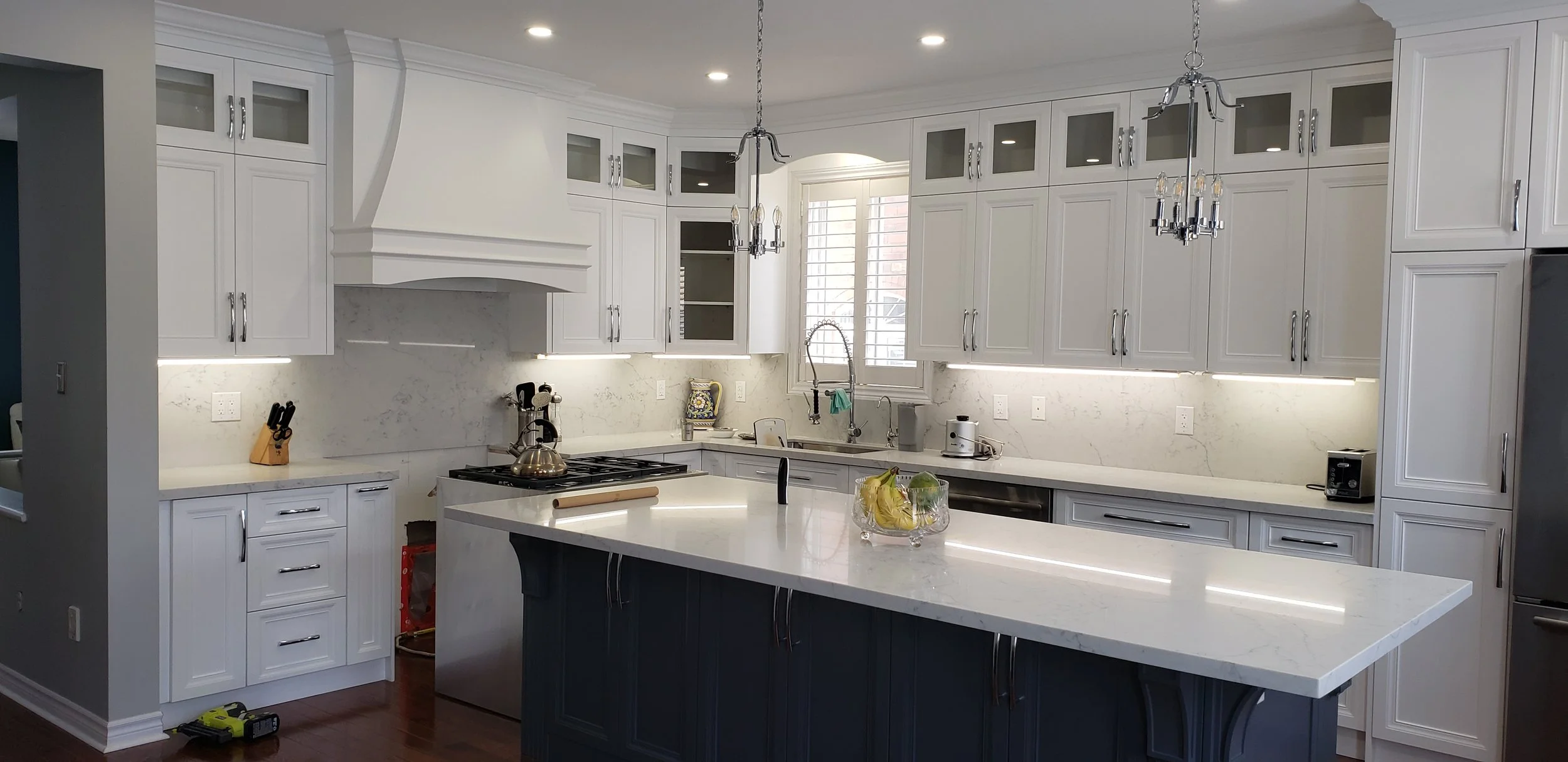 This clean, modern kitchen features sleek cabinetry paired with a luxury marble countertop and a stunning full-height marble waterfall backsplash, creating a seamless and refined look. The minimalist design is anchored by a stand-alone kitchen island
