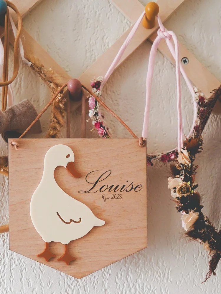 Fanion en bois avec canard et prénom, accroché dans une chambre d'enfant