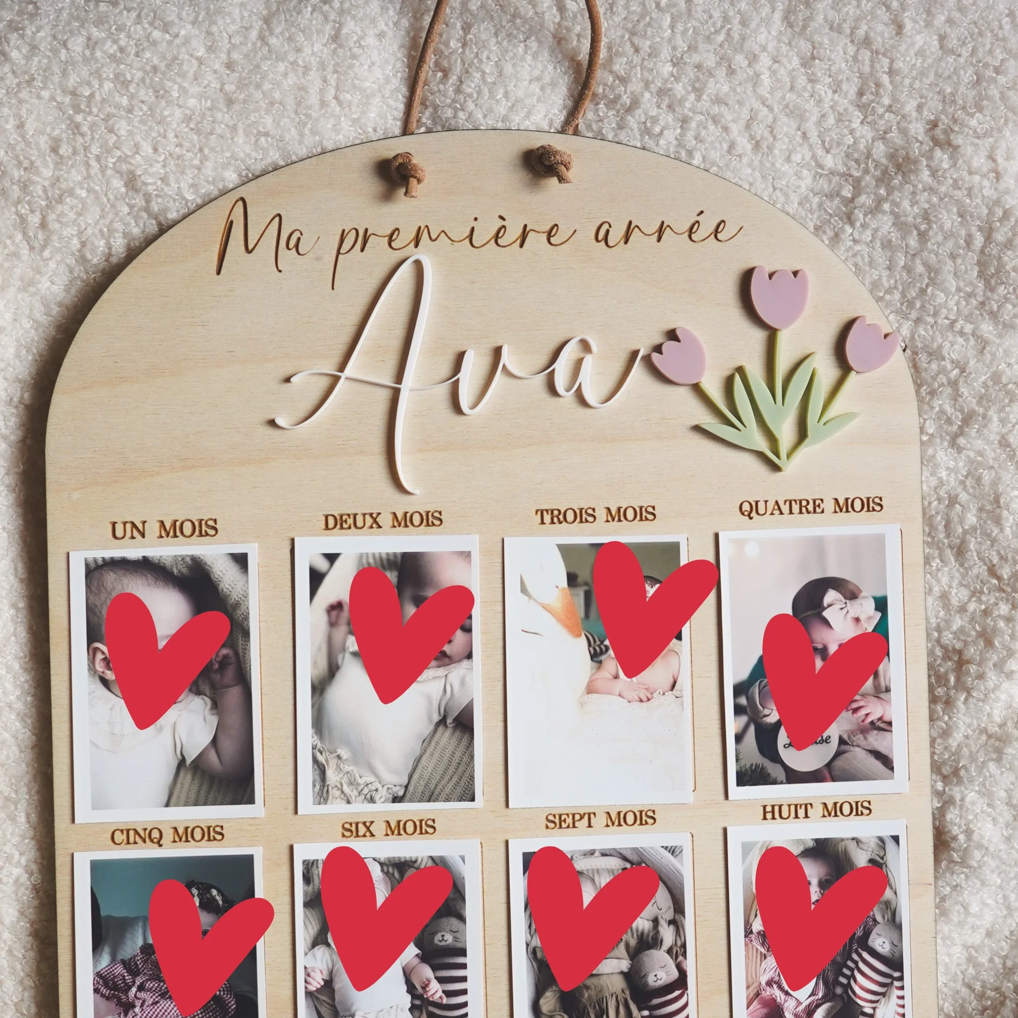Panneau à tulipes au prénom « Ava » posé sur un plaid, avec cordon de suspension et photos de bébé dans les cases