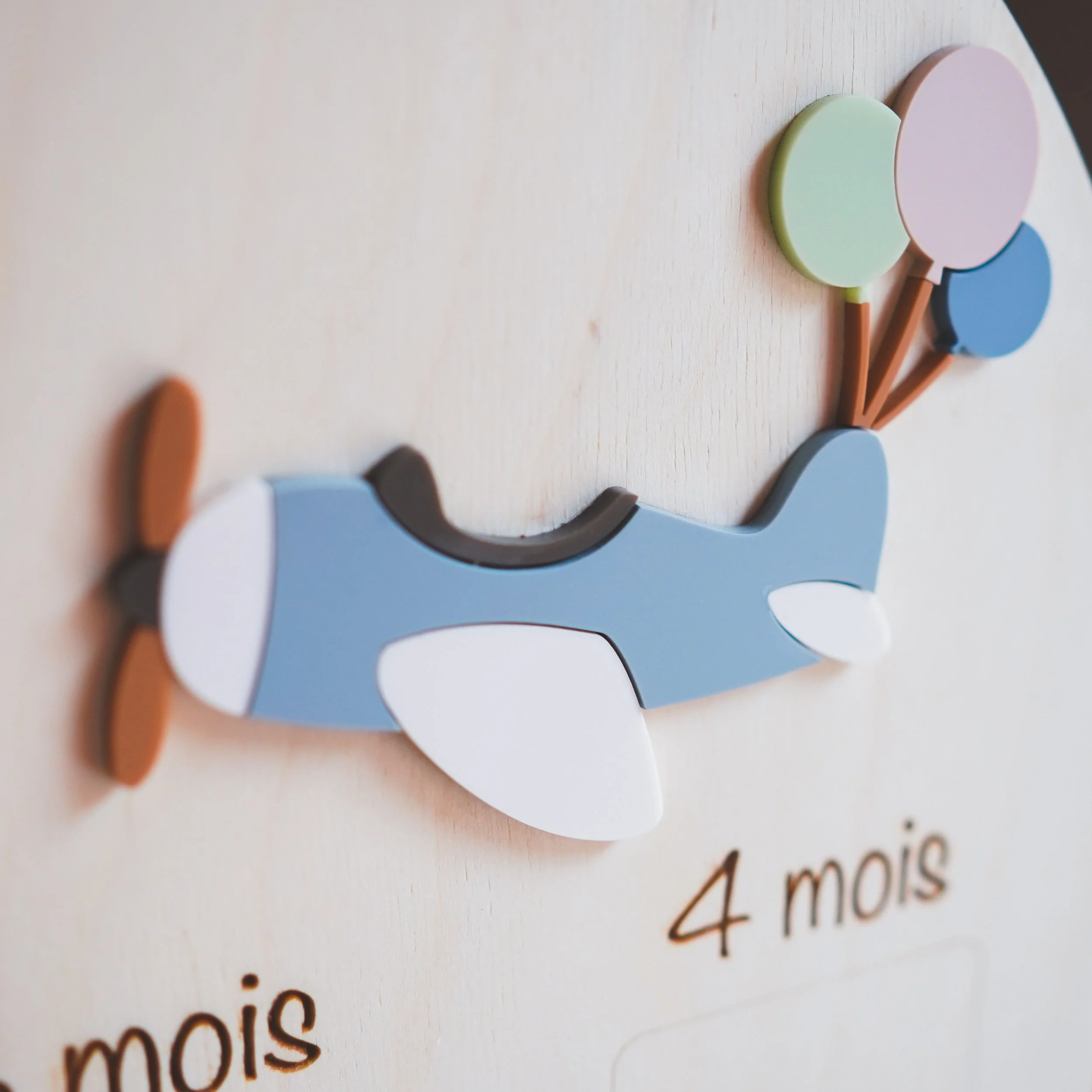 Avion bleu en bois avec trois ballons pastel sur le panneau photo bébé
