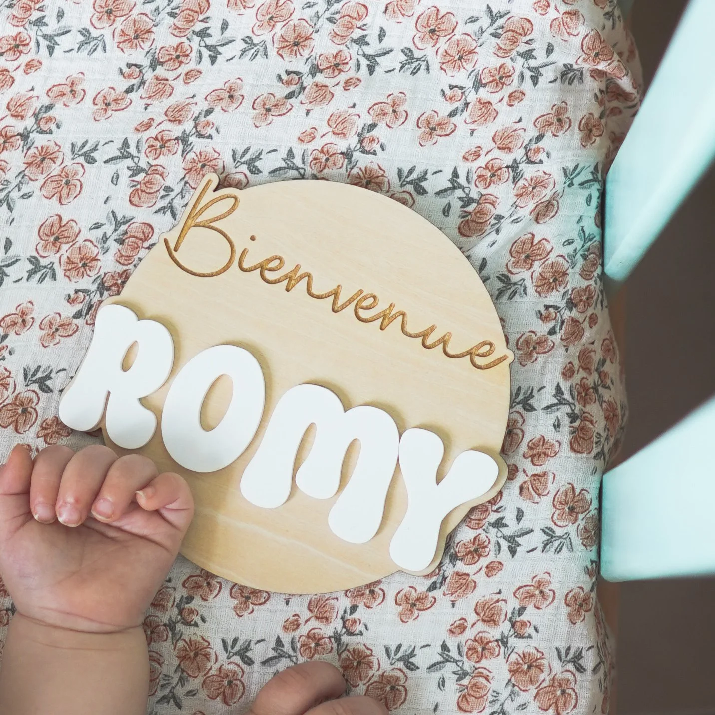 "Plaque en bois avec l'inscription 'Bienvenue Romy' sur tissu à motifs floraux."