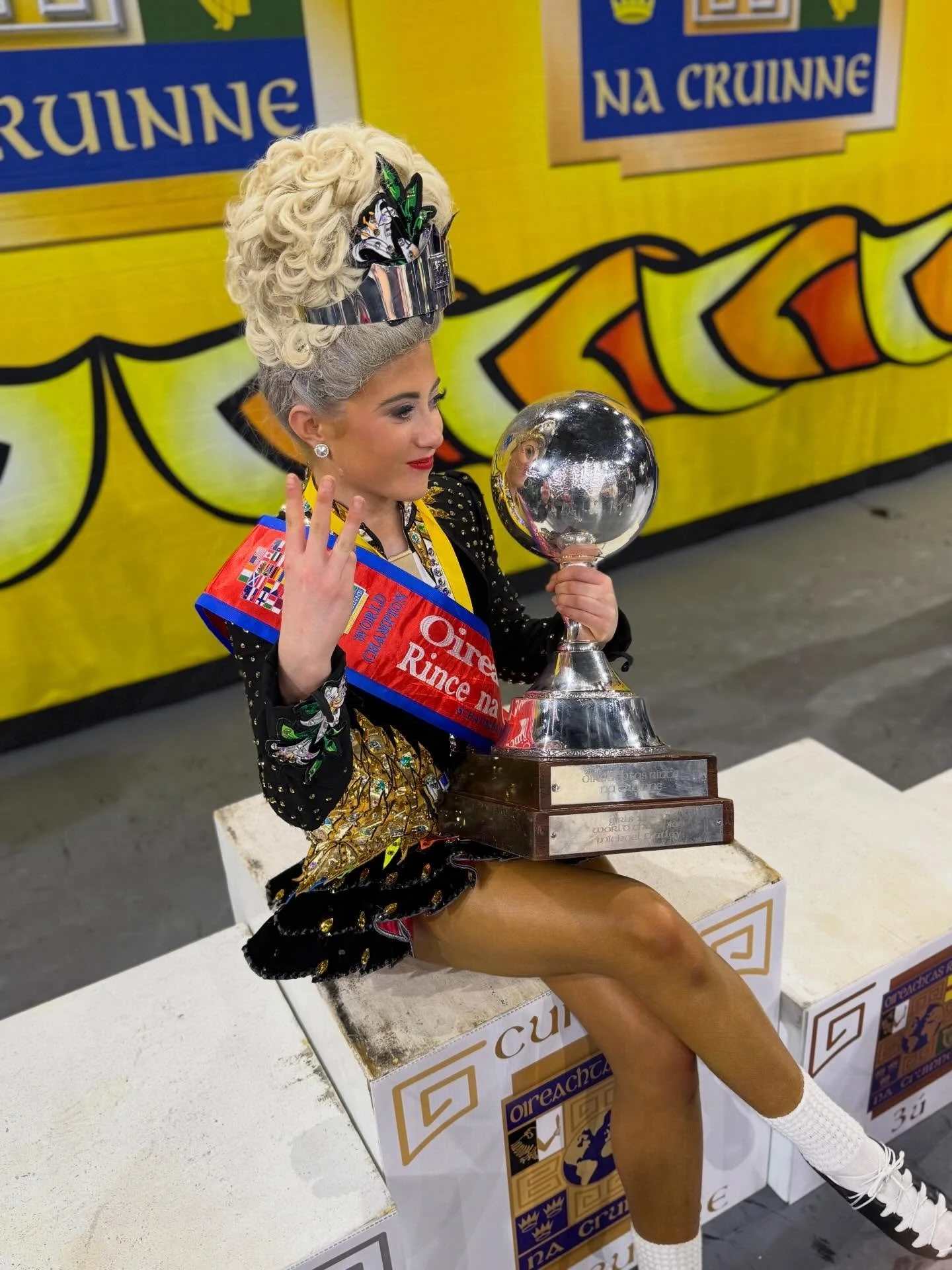 A young Irish dancer holding a globe celebrating her third World Championship title.