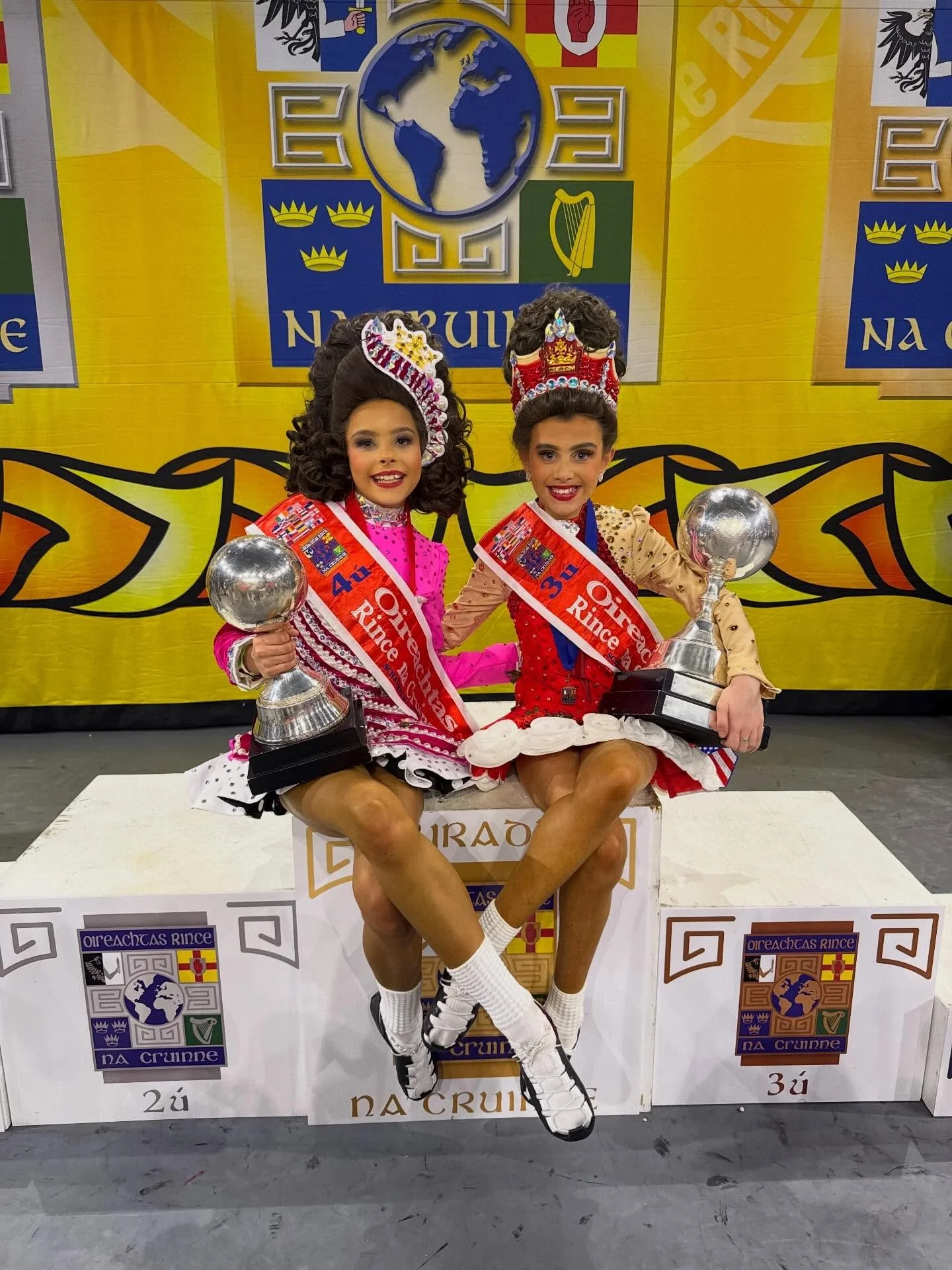 Two young girls celebrating 3rd and 4th placements holding globes at the World Irish Dance Championships 2026.