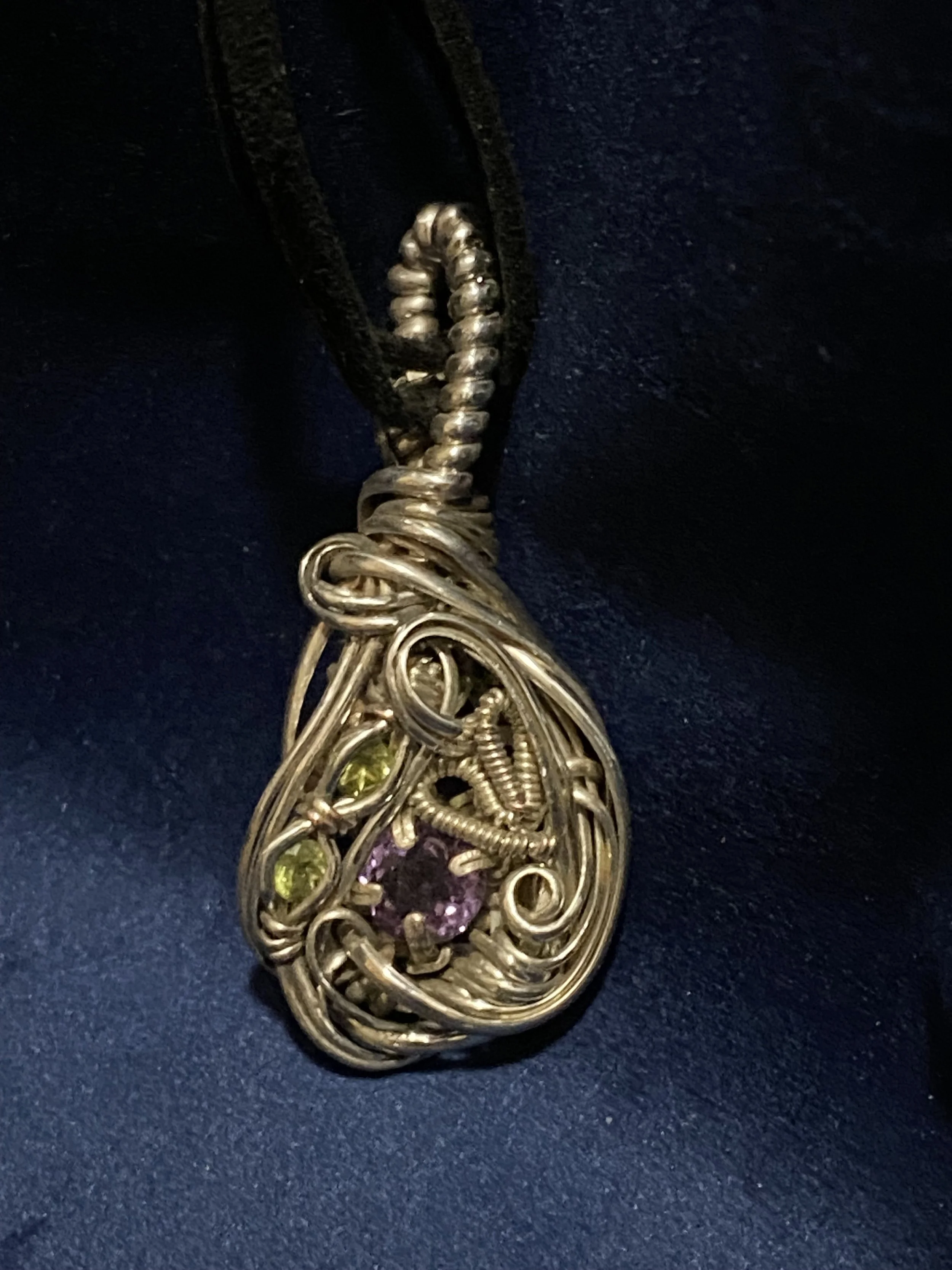 Flowy wire wrapped pendant featuring (2) round cut peridot and a single round amethyst, in sterling silver