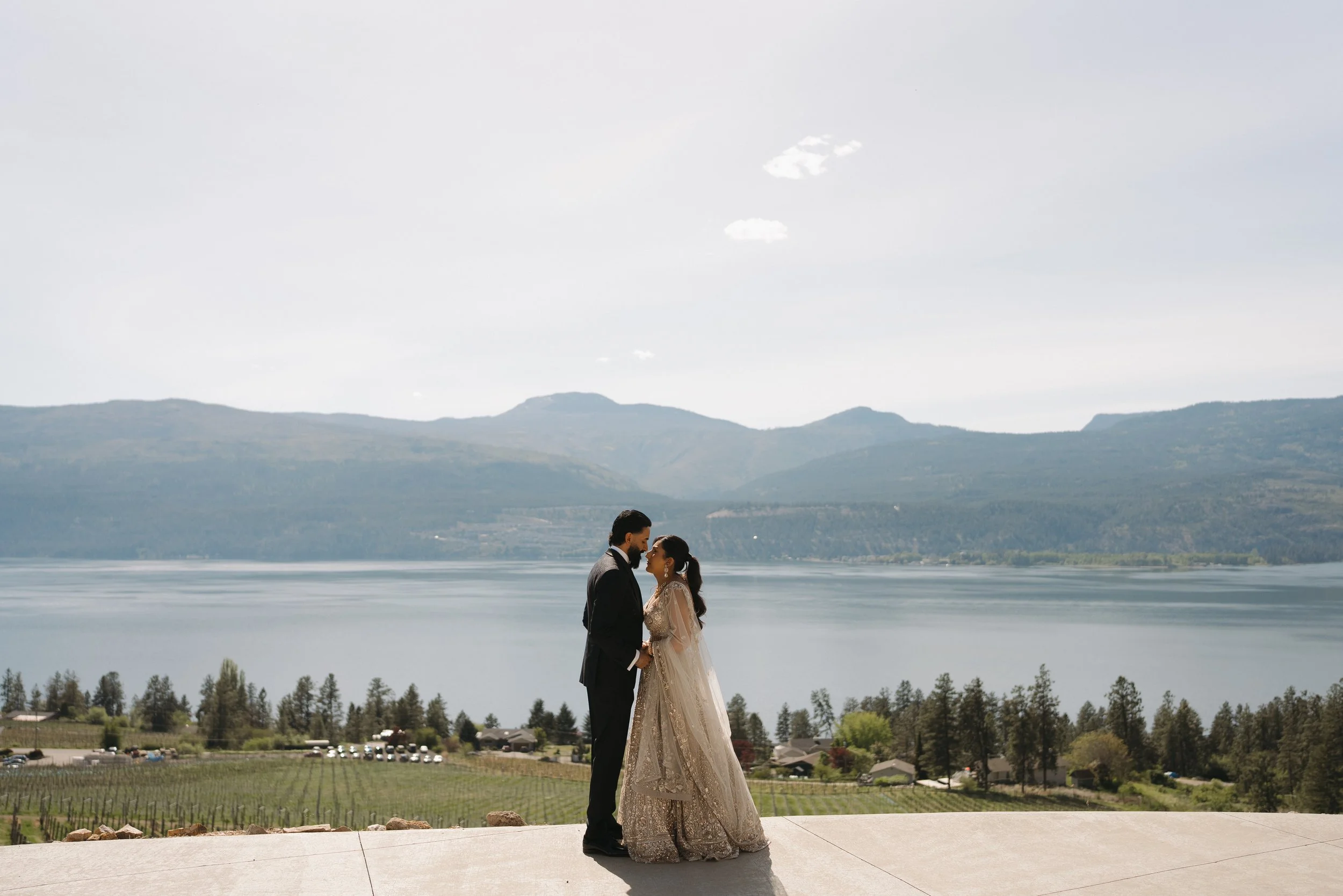 Reena & Nov standing together with views of the Okanagan landscape