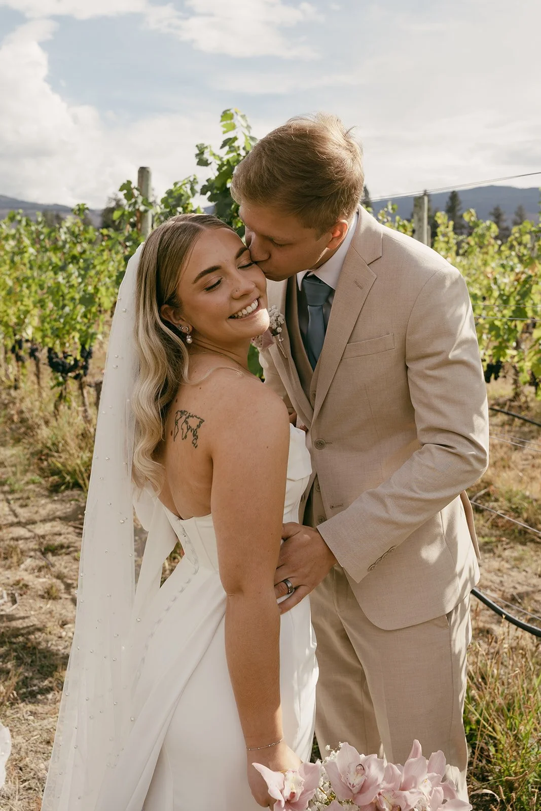 Newlyweds embracing in the vineyard at golden hour