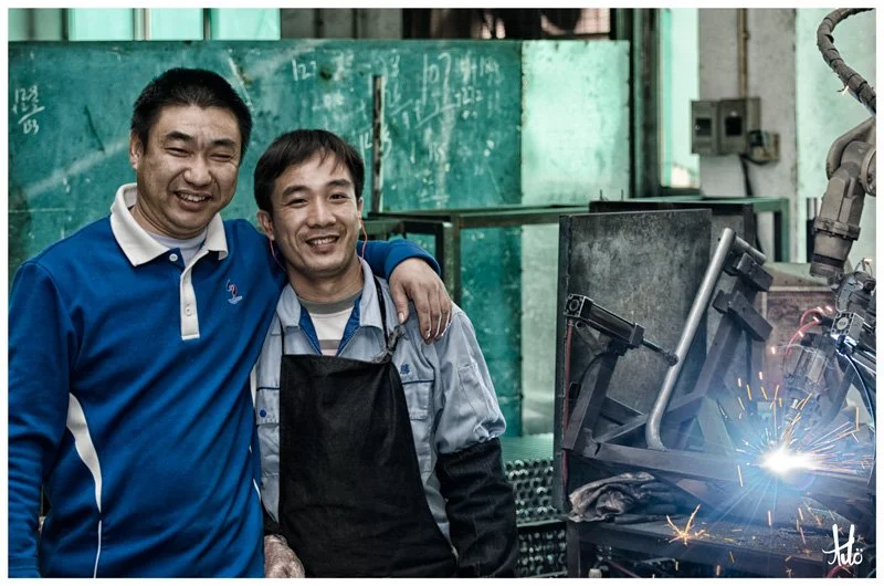 Fabrication group leader with robot welding machine operator.