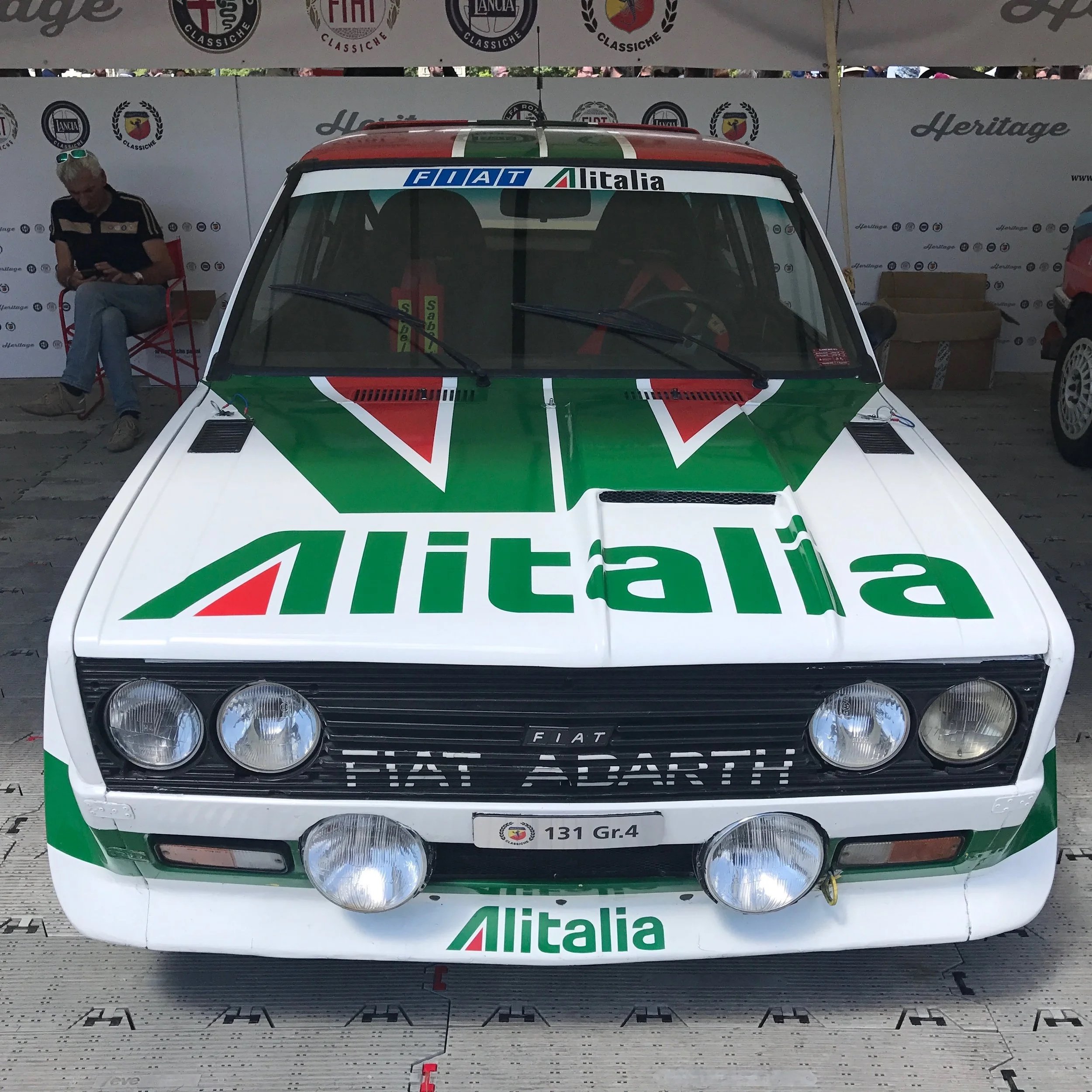 A race car decorated with the Italian colors and sponsorship logos, displayed at a motorsport event.