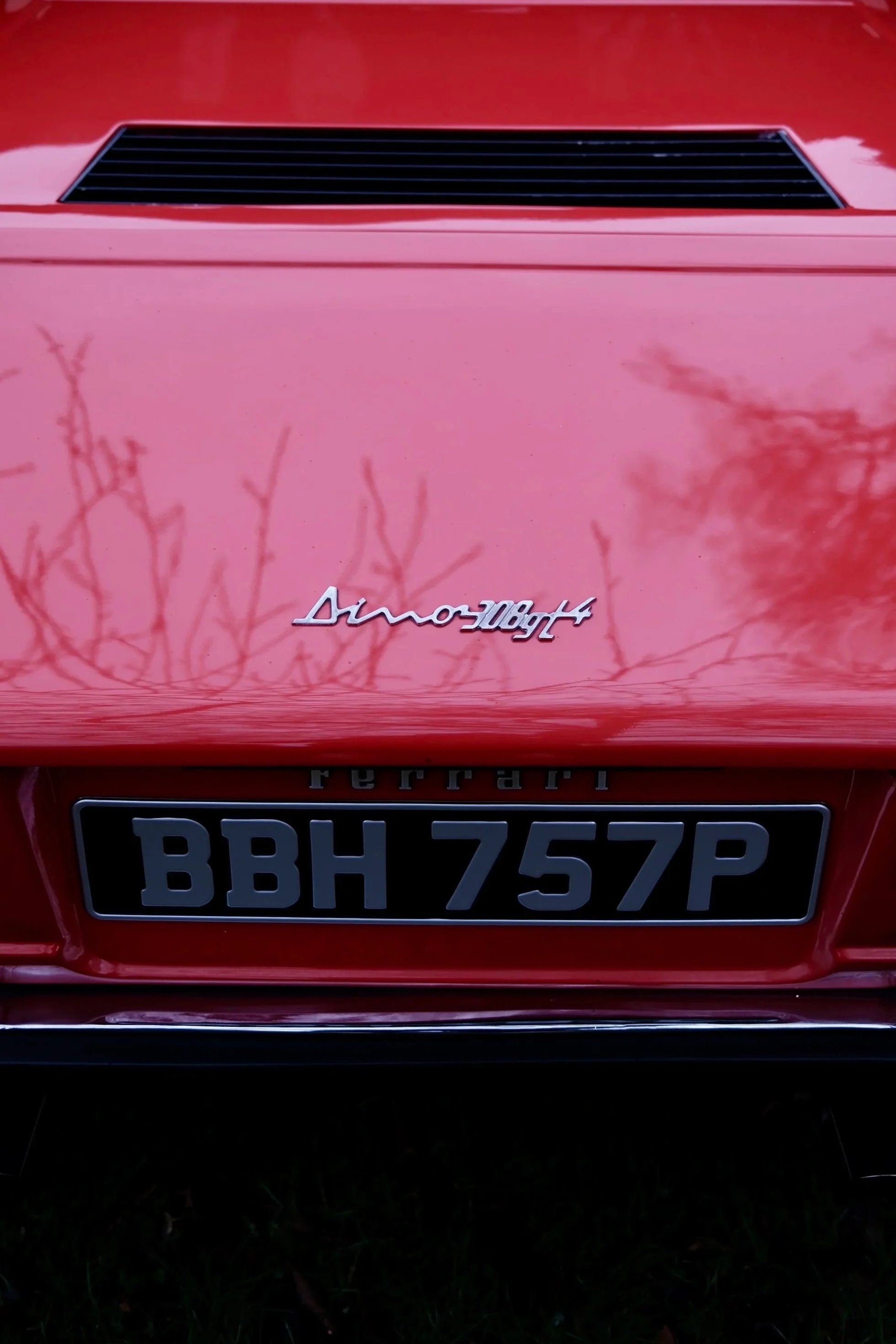 Close-up of the rear of a red Ferrari with a black license plate that reads BBH75P, and a Ferrari badge visible above the license plate.