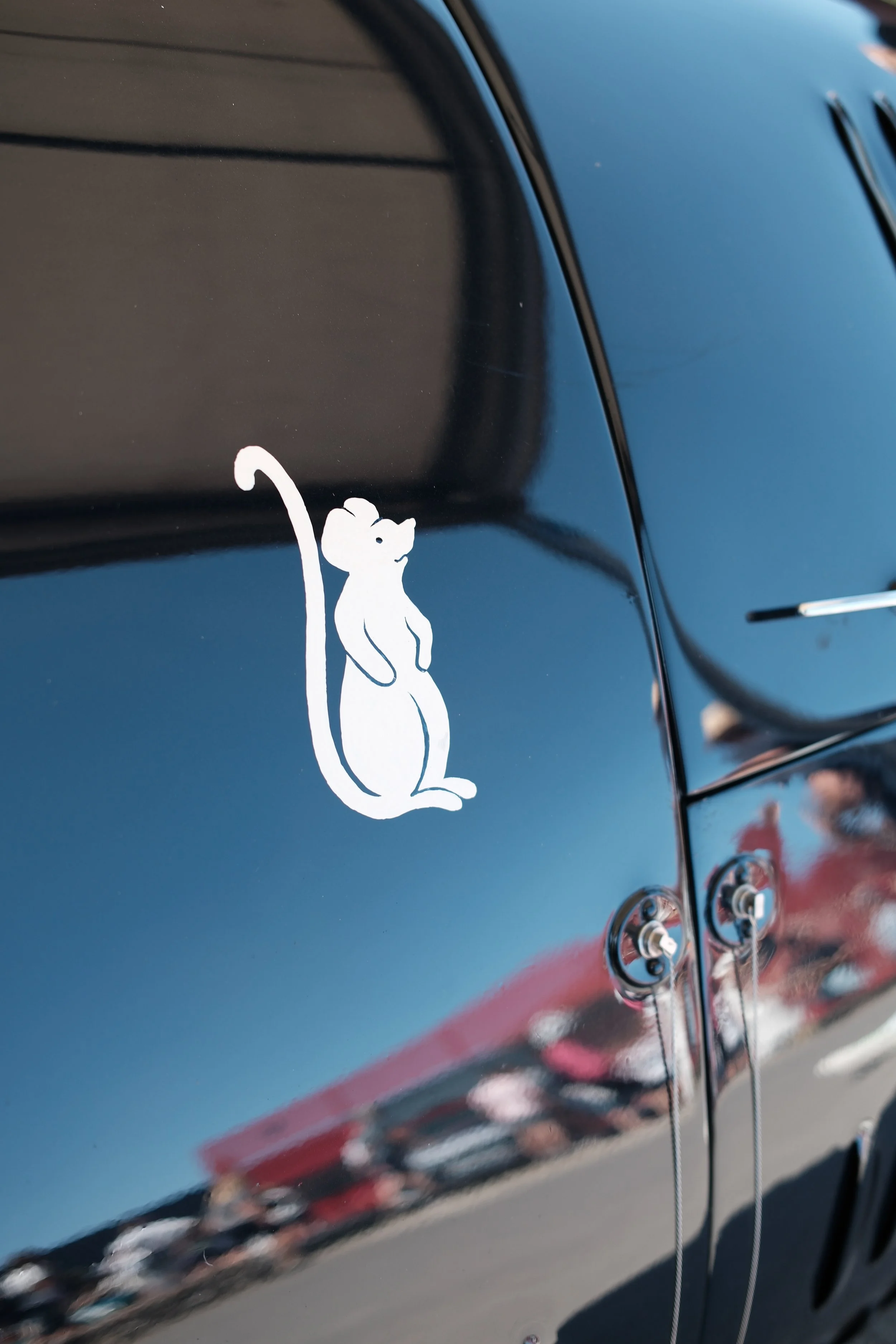A close-up of a black car with a white mouse-shaped decal.
