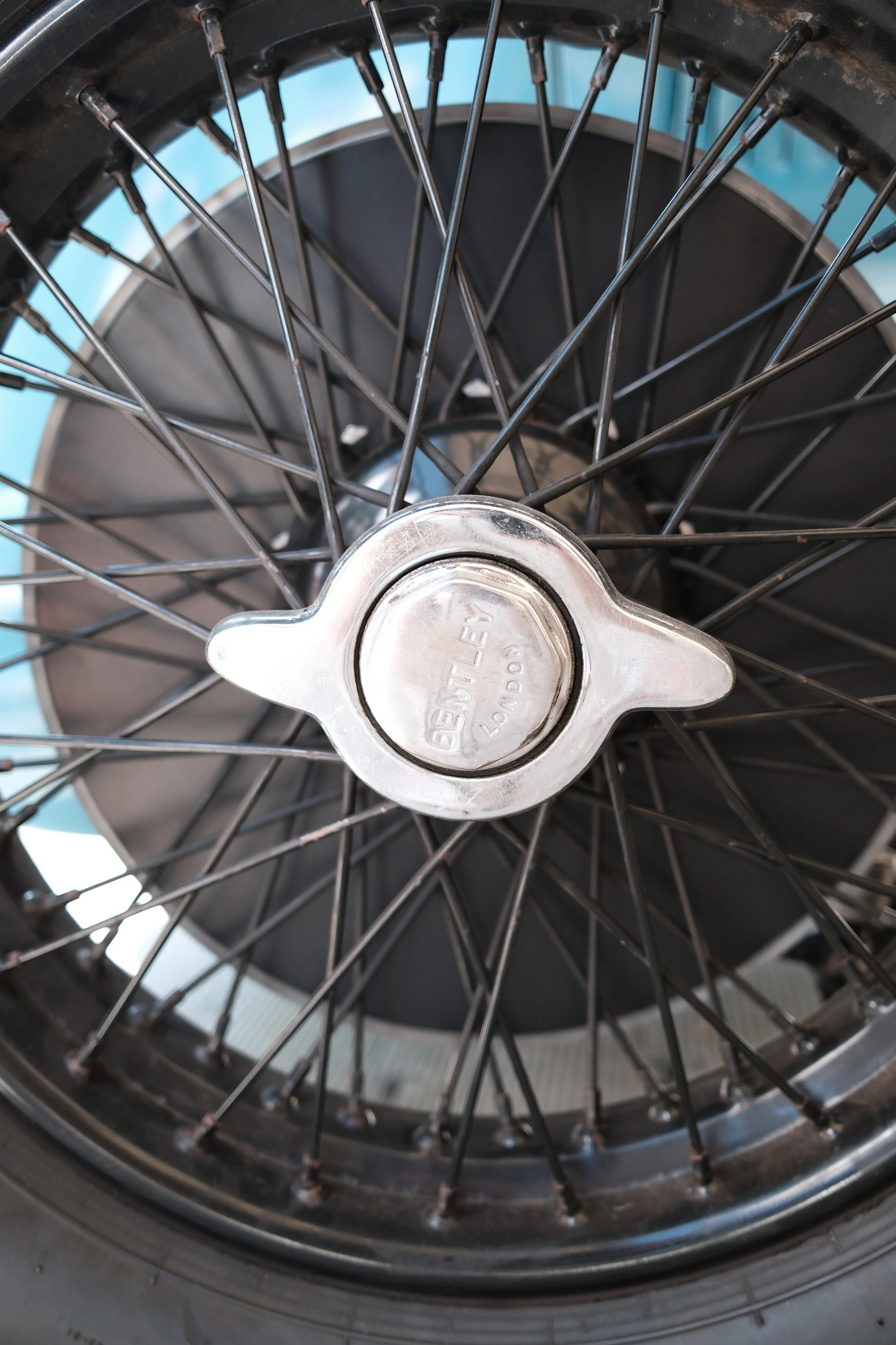 A close-up view of a bicycle wheel with spokes and a metal hub cap.