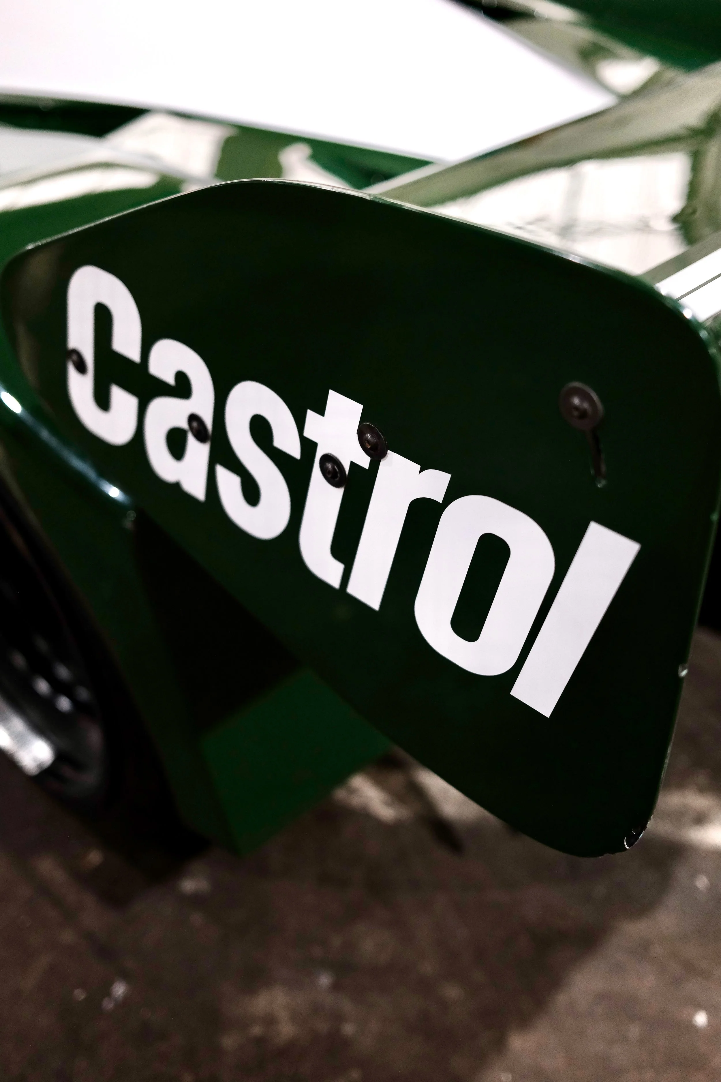 Close-up of a green object with white and black text that says 'restore' or similar, with a blurred background including parts of the ground.