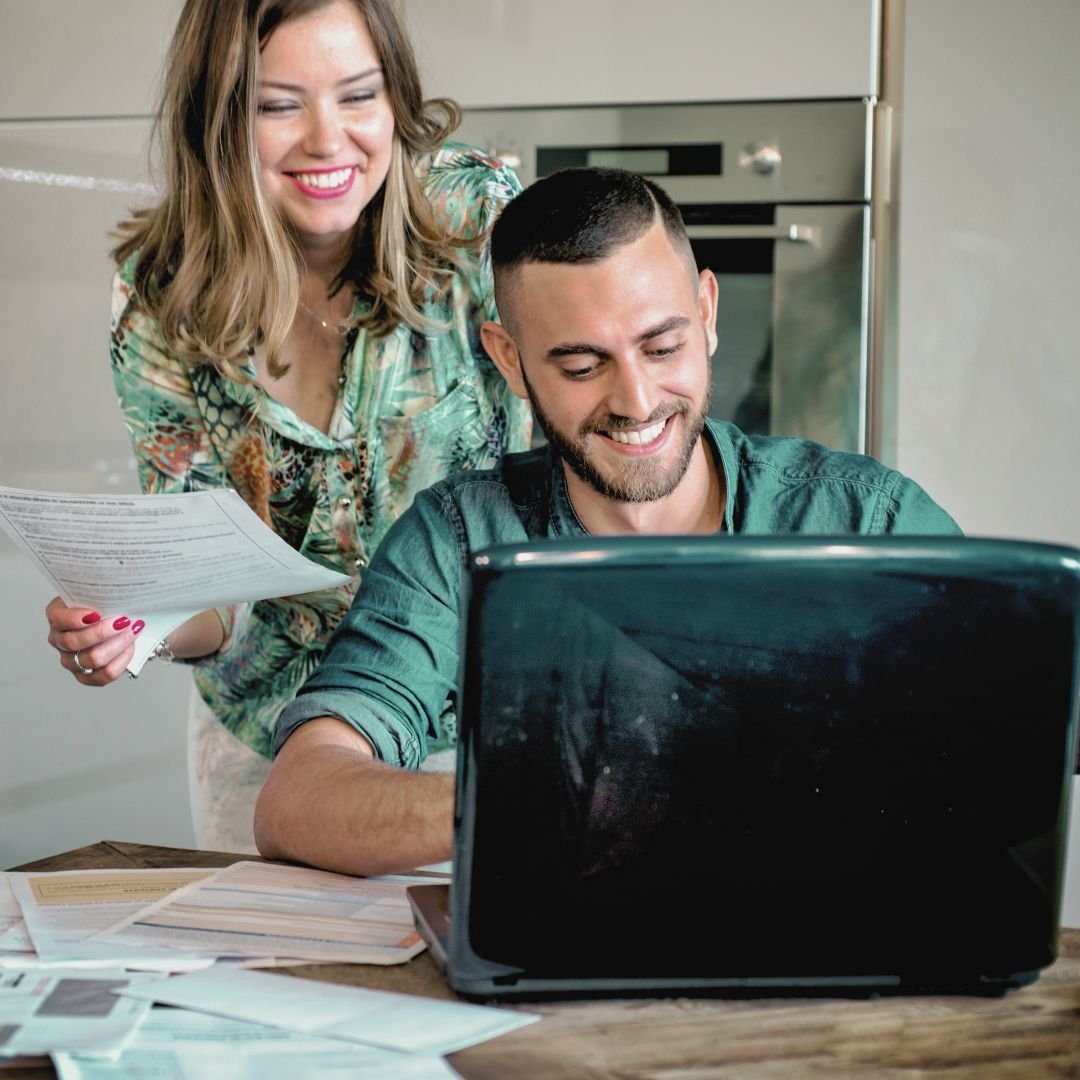 Couple looking at laptop with women holding papers