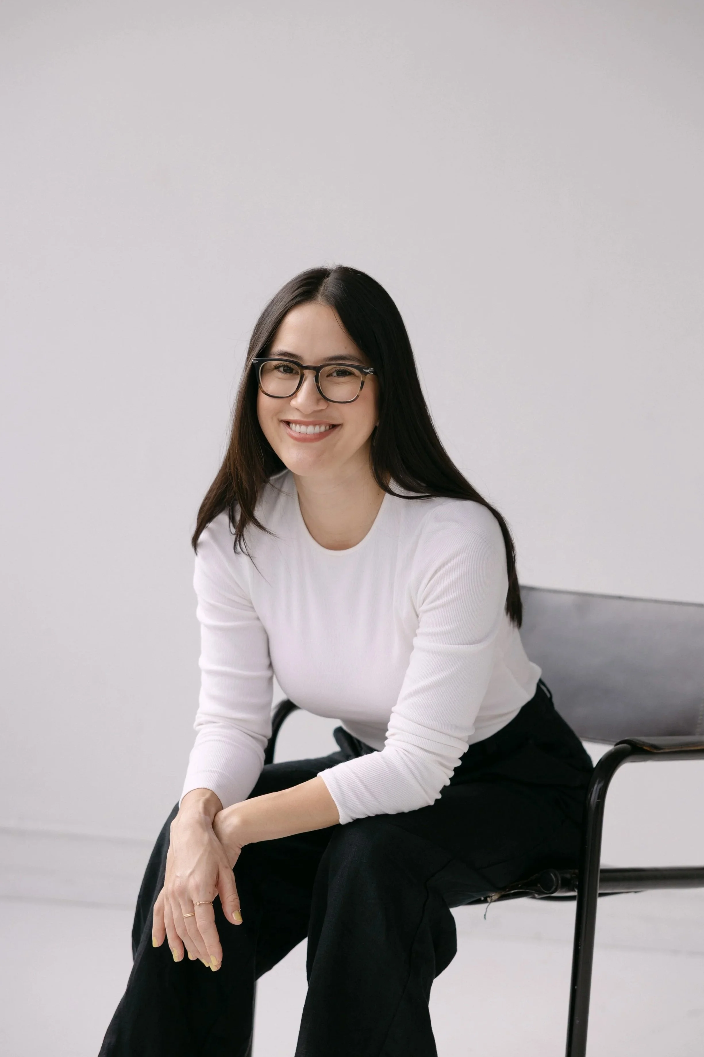 MaiLinh Hartz, a BIPOC woman therapist, seated and smiling in a clean, light-filled studio setting.